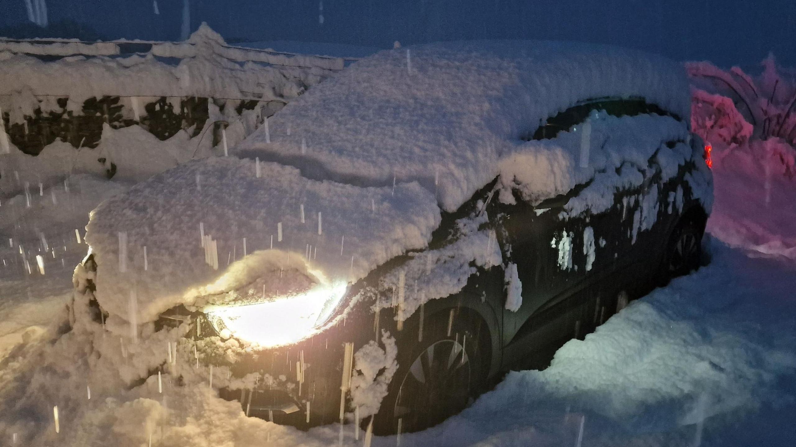 Thick snow on top of car, while it snows