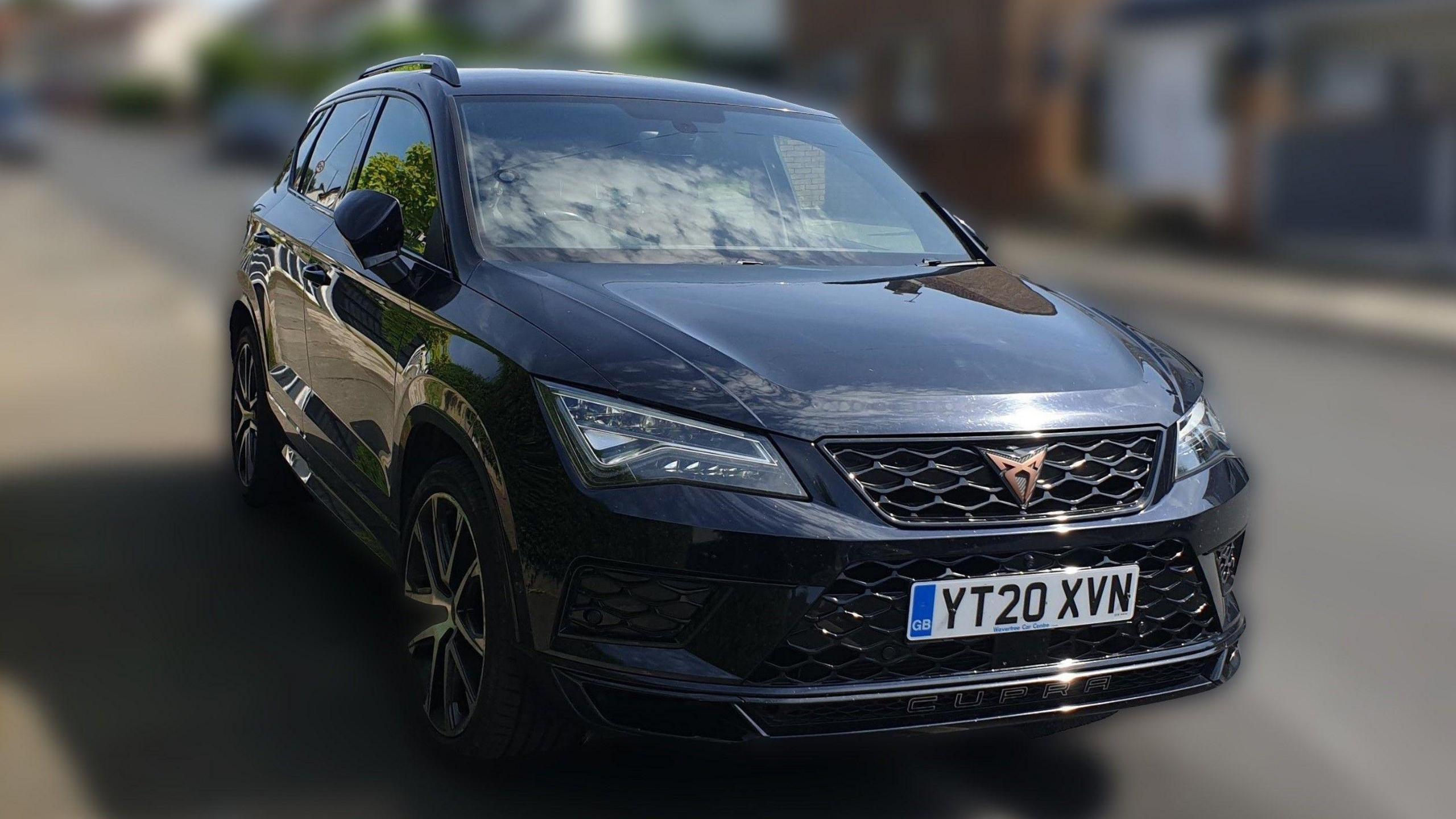 A dark coloured Seat Alteca Cupra car driving against a blurred background