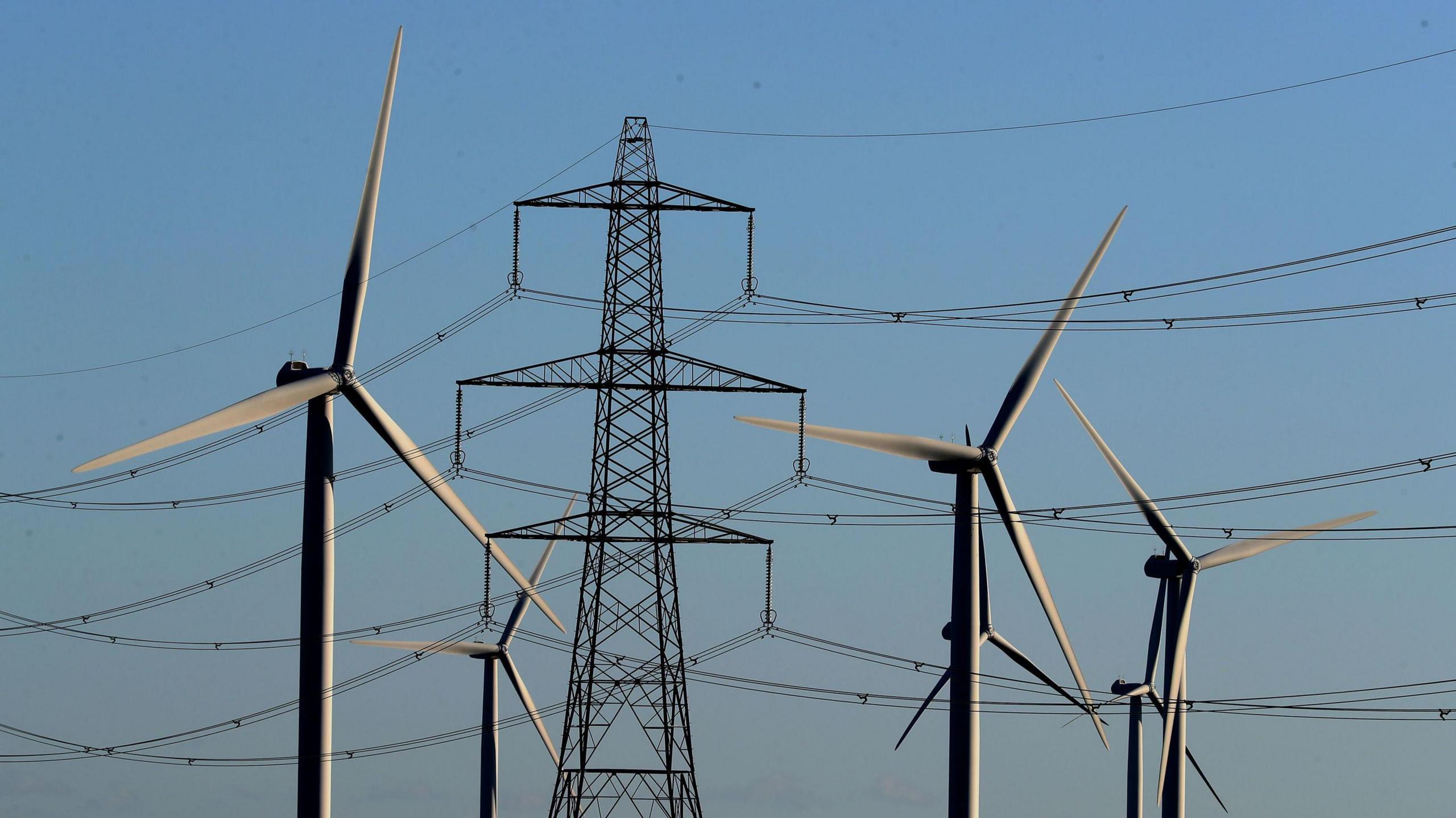 A pylon with four windturbines around it.