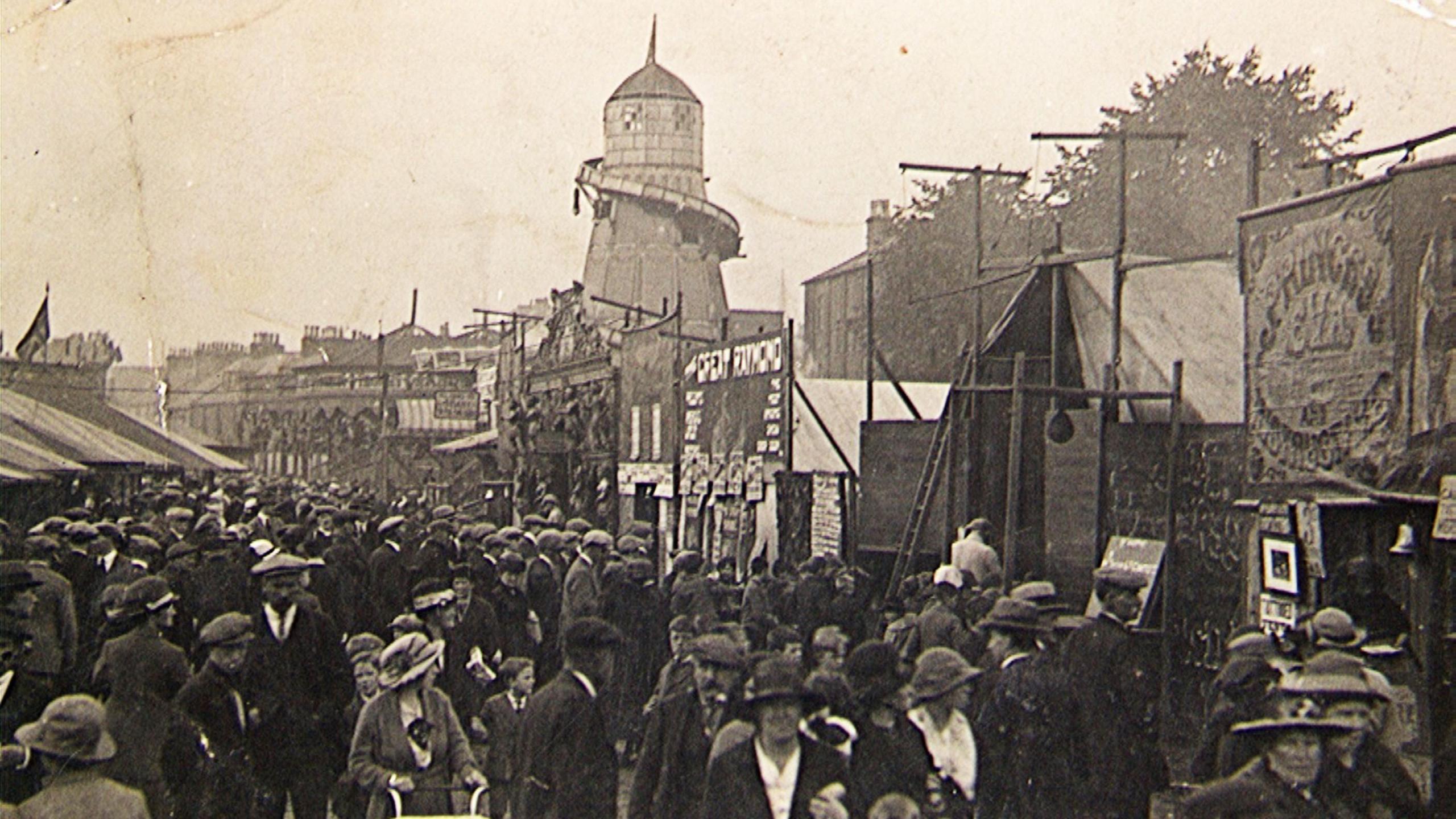 A black and white picture of a fairground in Dumfries with hundreds of people milling around