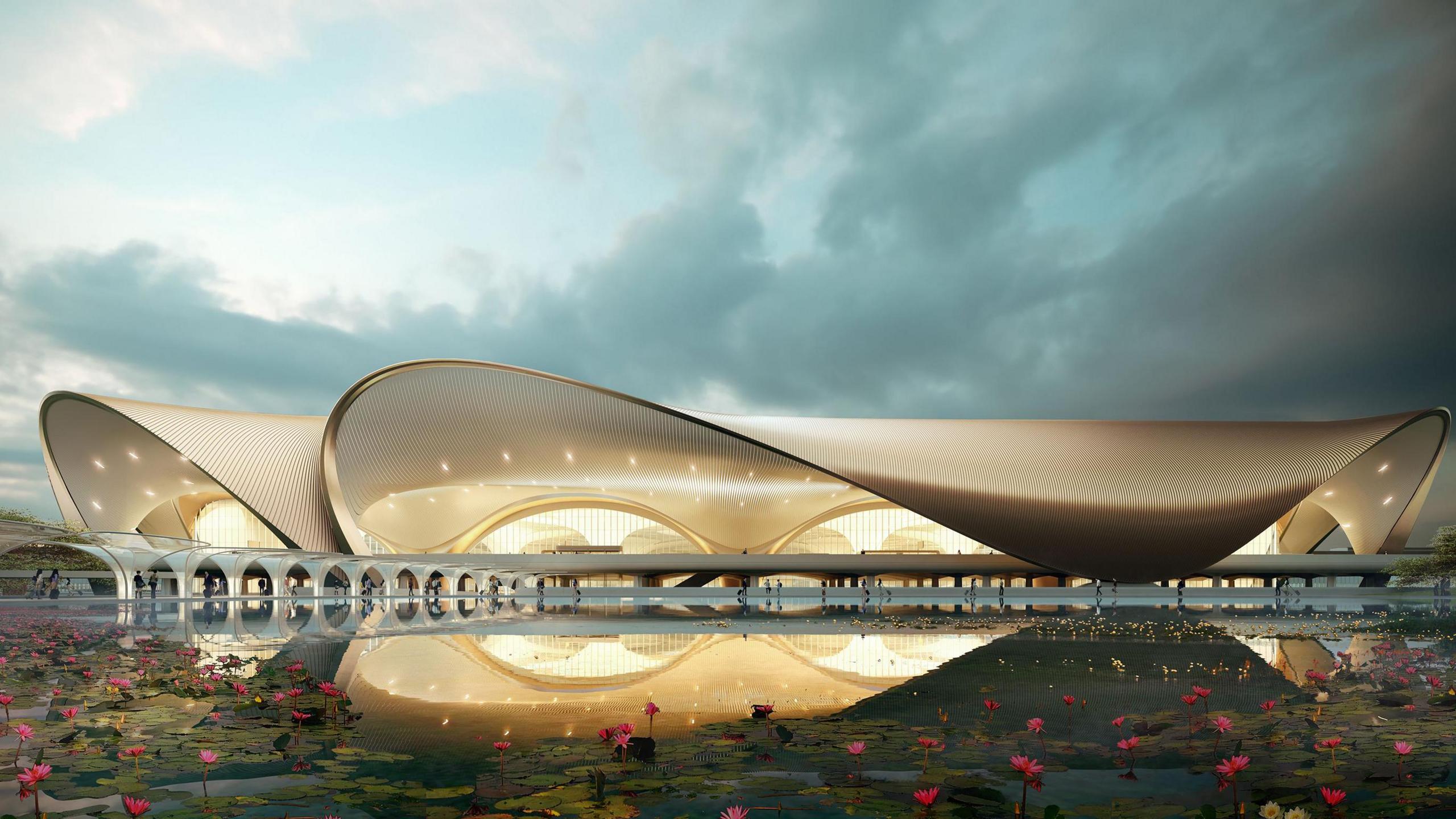 Image of the lotus shaped exterior of the Navi Mumbai International Airport, lit up at dusk. 