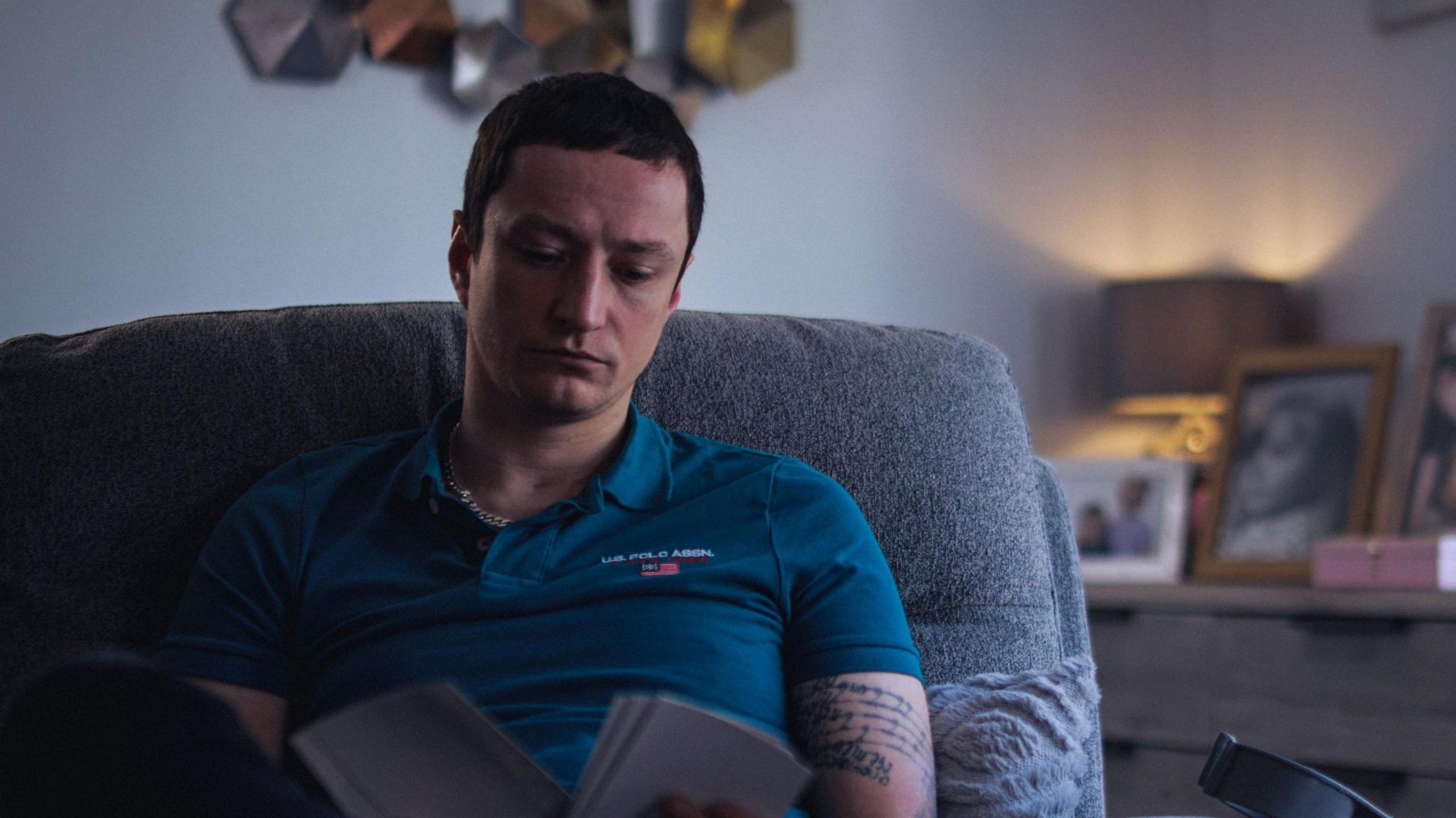 Scott Peden sitting on a chair looking at book