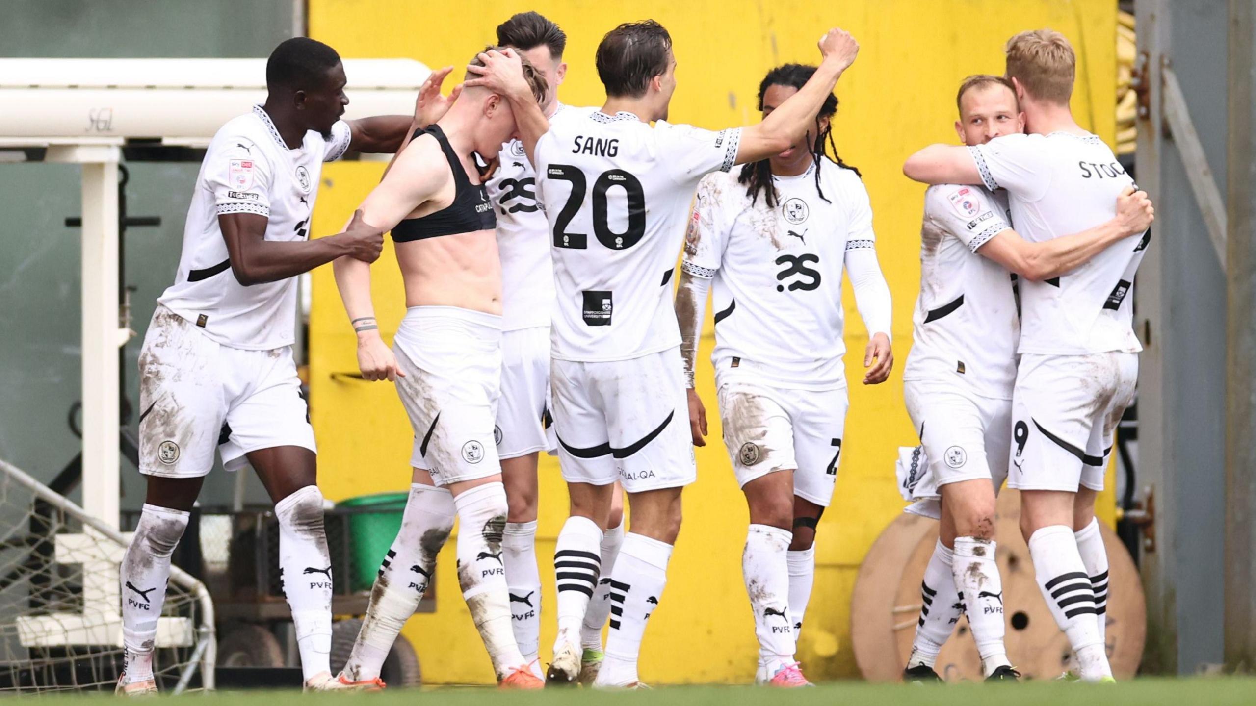 Port Vale players in white shirts celebrate scoring their goal against Morecambe