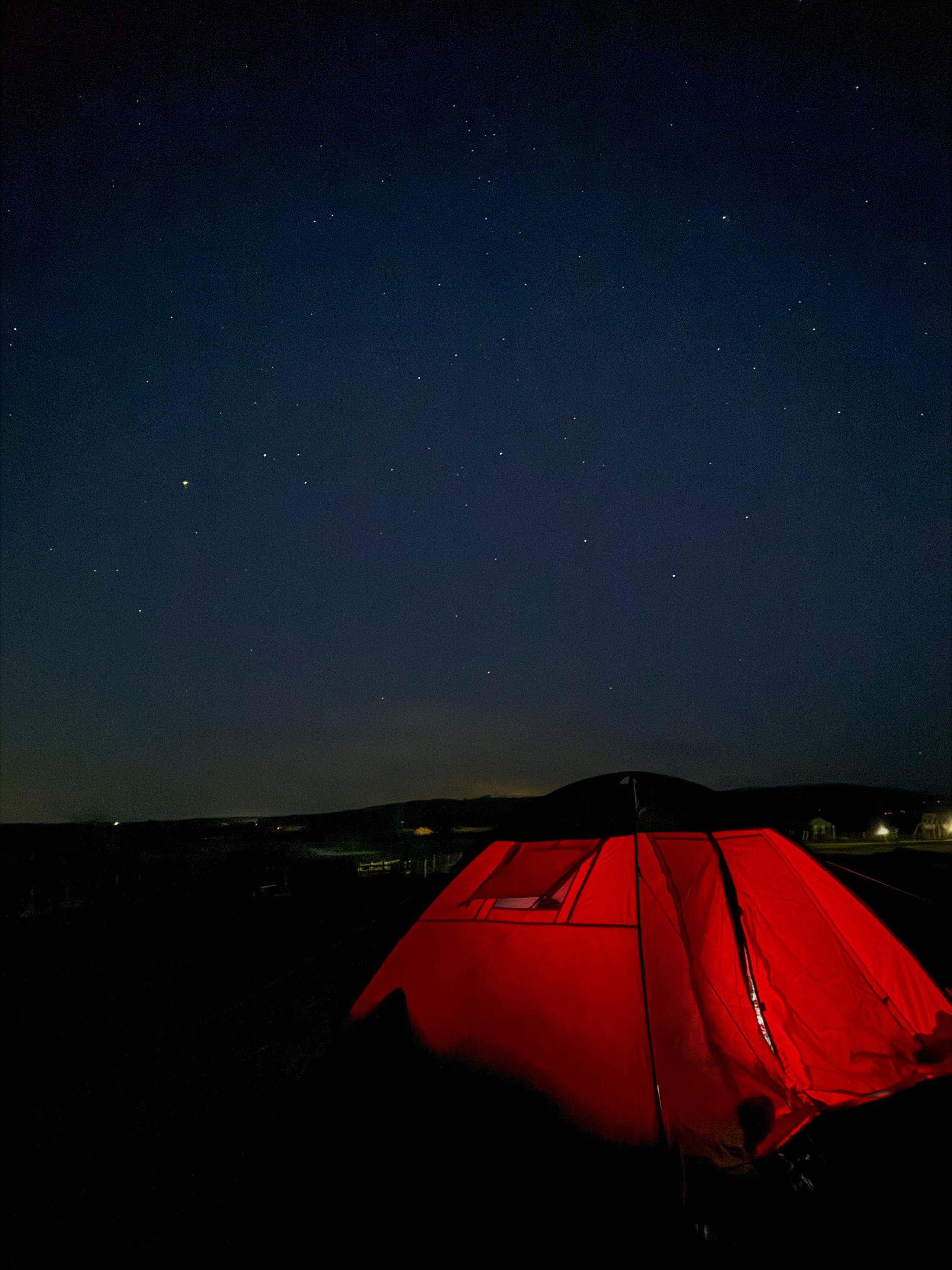 Red tent below a starry night sky