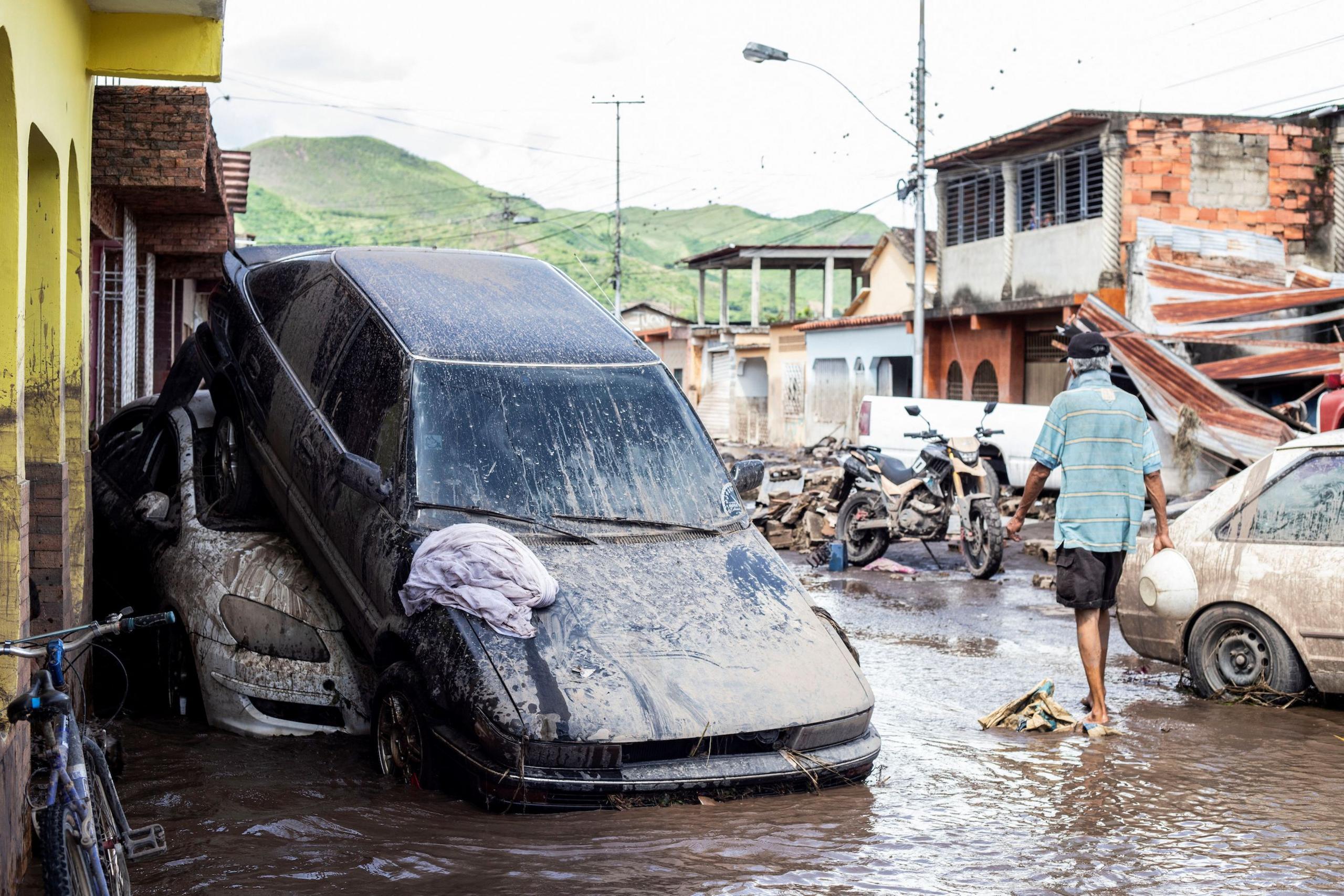 Muddy cars sit on top of each other in flooded streets