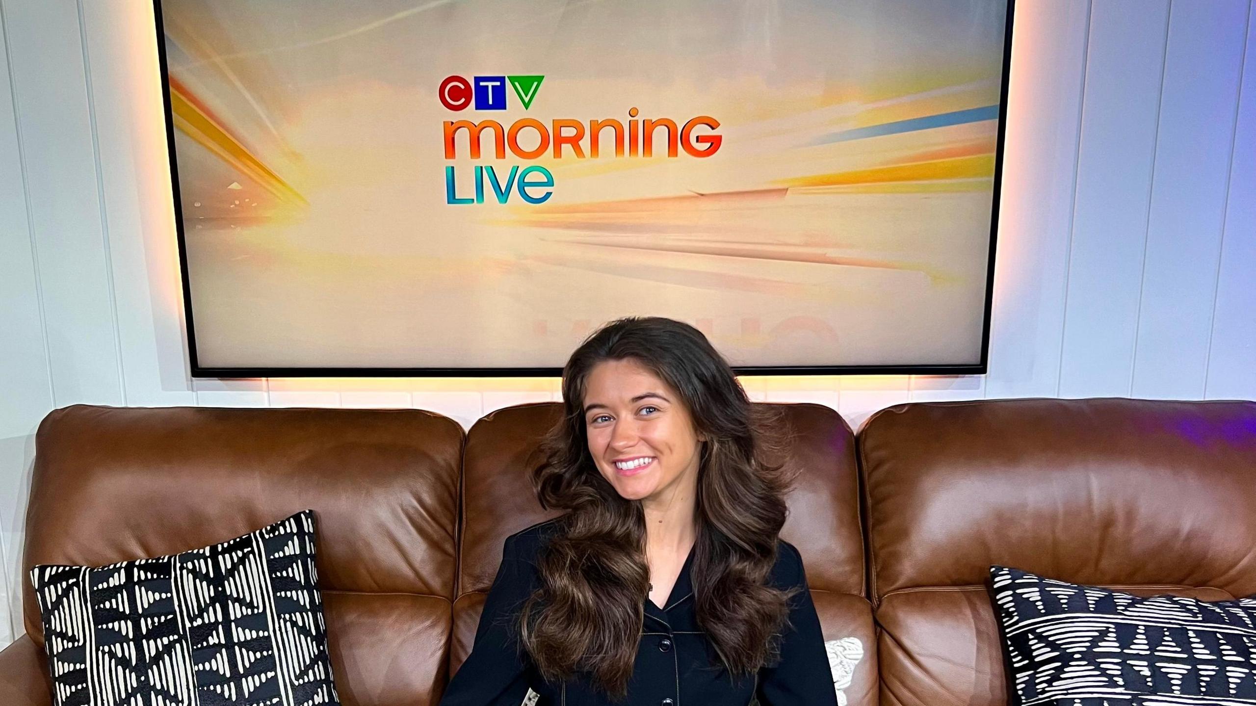 Clíodhna Ní Chorráin sits on a brown sofa wearing a black blazer underneath a sign that says 'CTV Morning Live'.