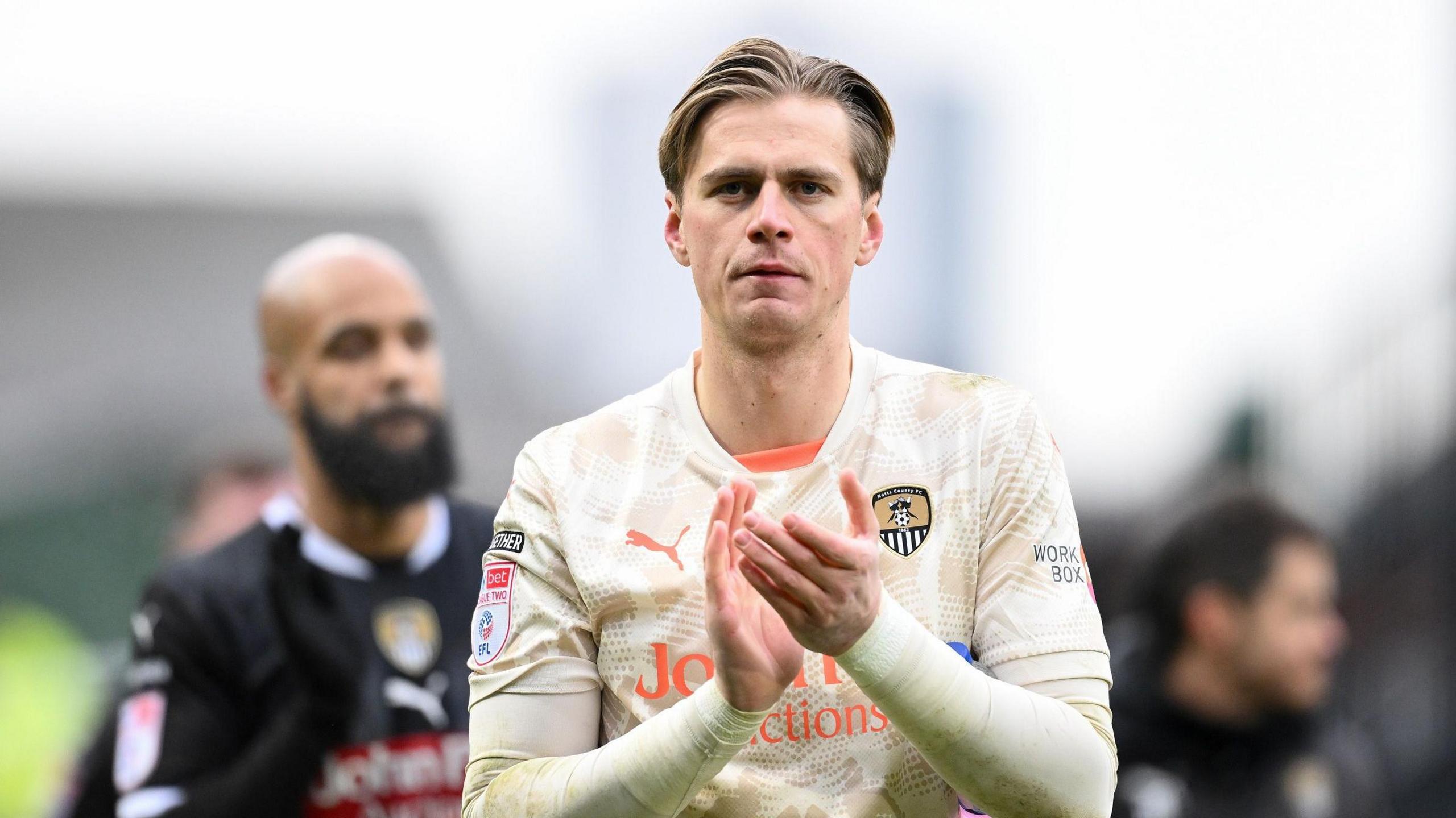 Alex Bass applauds Notts County fans as he leaves the pitch