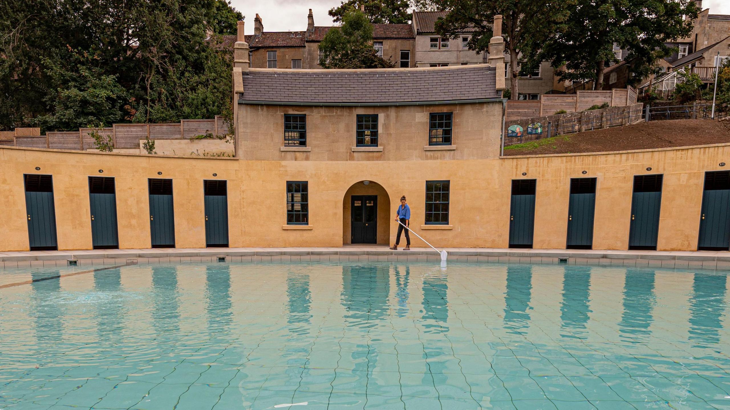A swimming pool inside Cleveland Pools lido, and in the background are the changing rooms and the house in traditional Georgian architecture