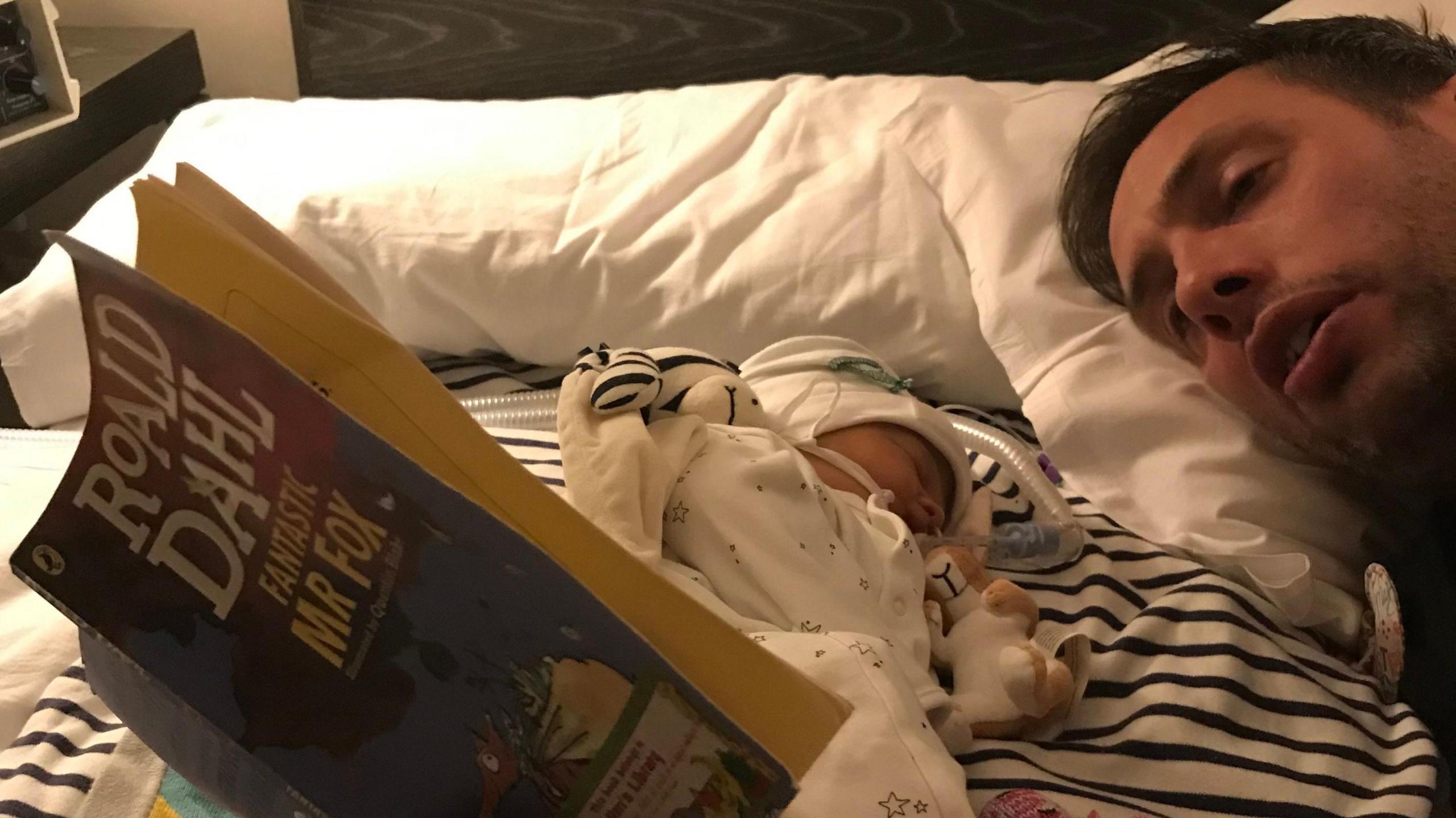 Ryan Lock, lying beside his baby daughter Ida, is photographed reading Roald Dahl's Fantastic Mr Fox.