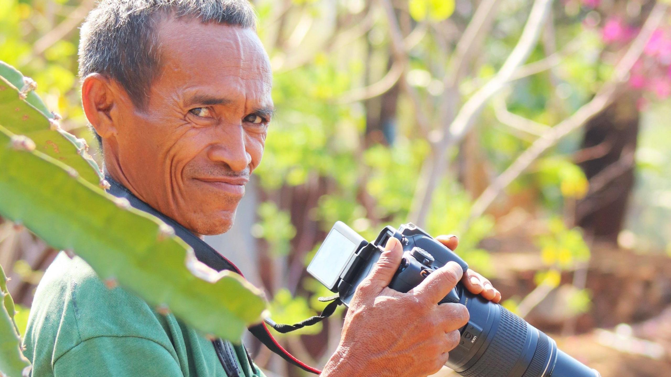 Faustino Mauloko da Cunha holds a telephoto camera