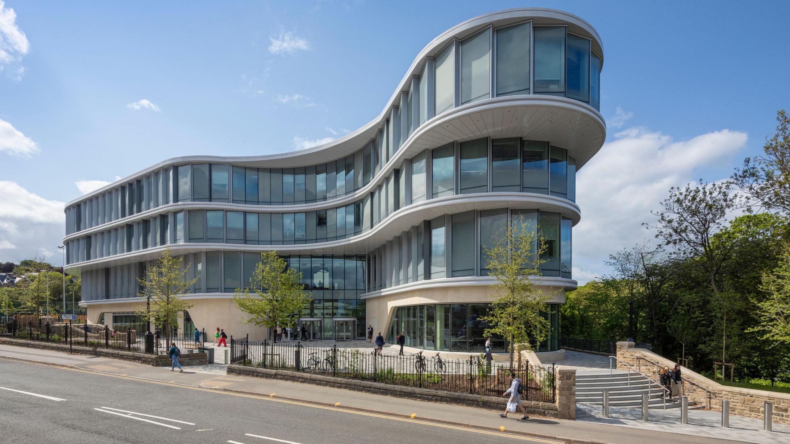 A three-storey, glass-fronted building, shaped in a curve.