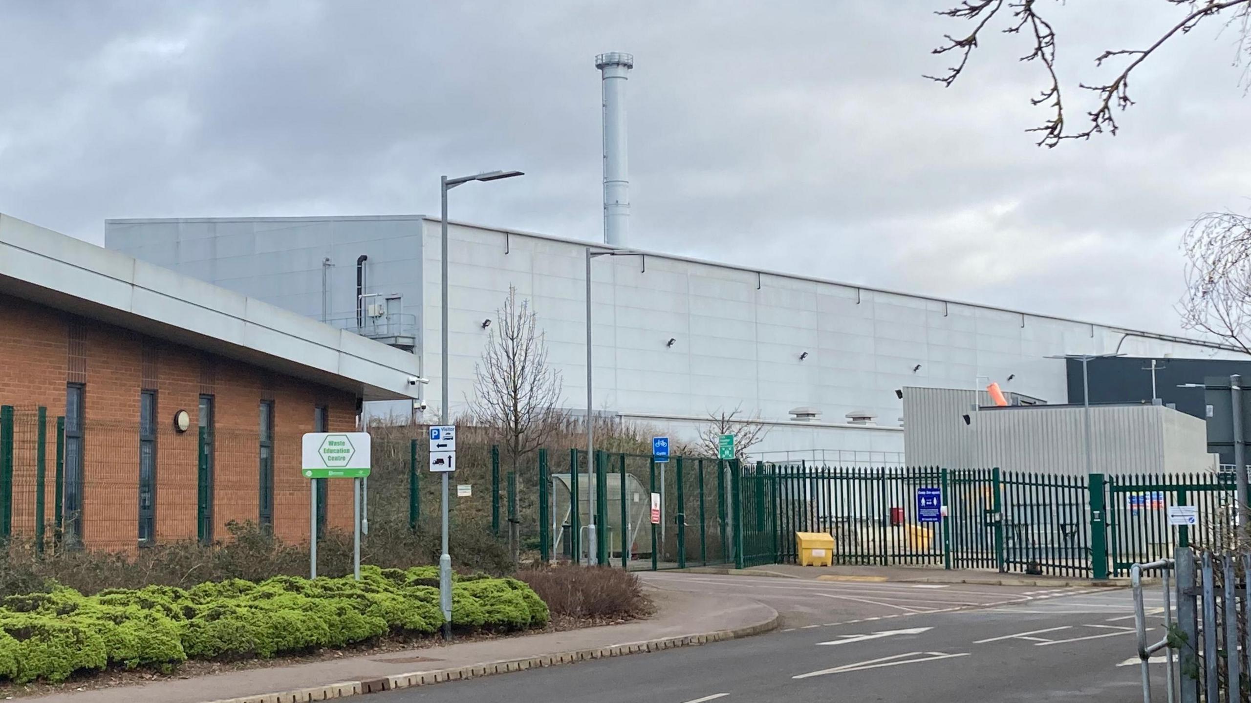 A large grey building with a tall grey chimney