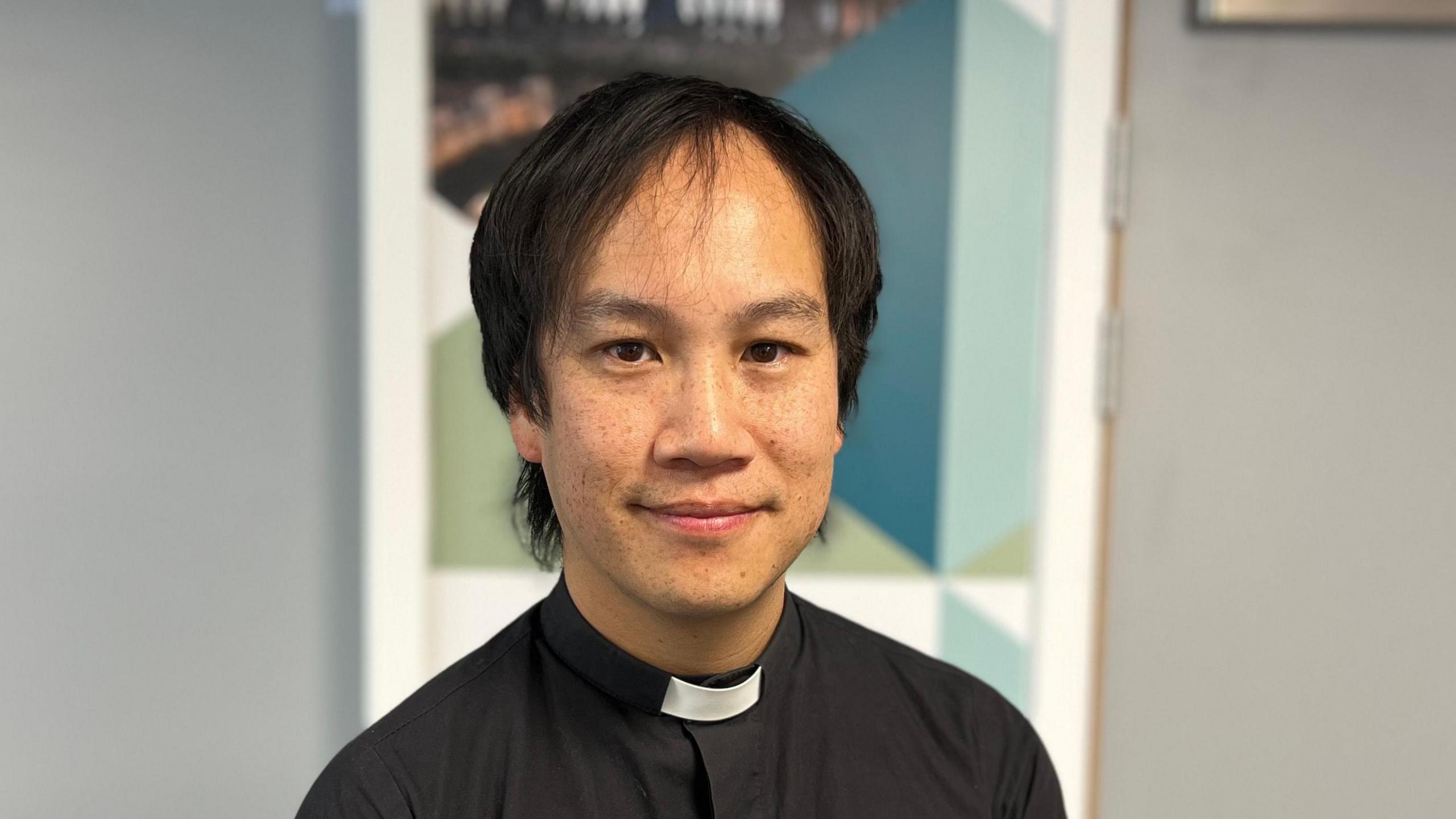 A picture of Mark Nam, wearing a dog collar and black shirt, in the BBC Radio Berkshire studios.
