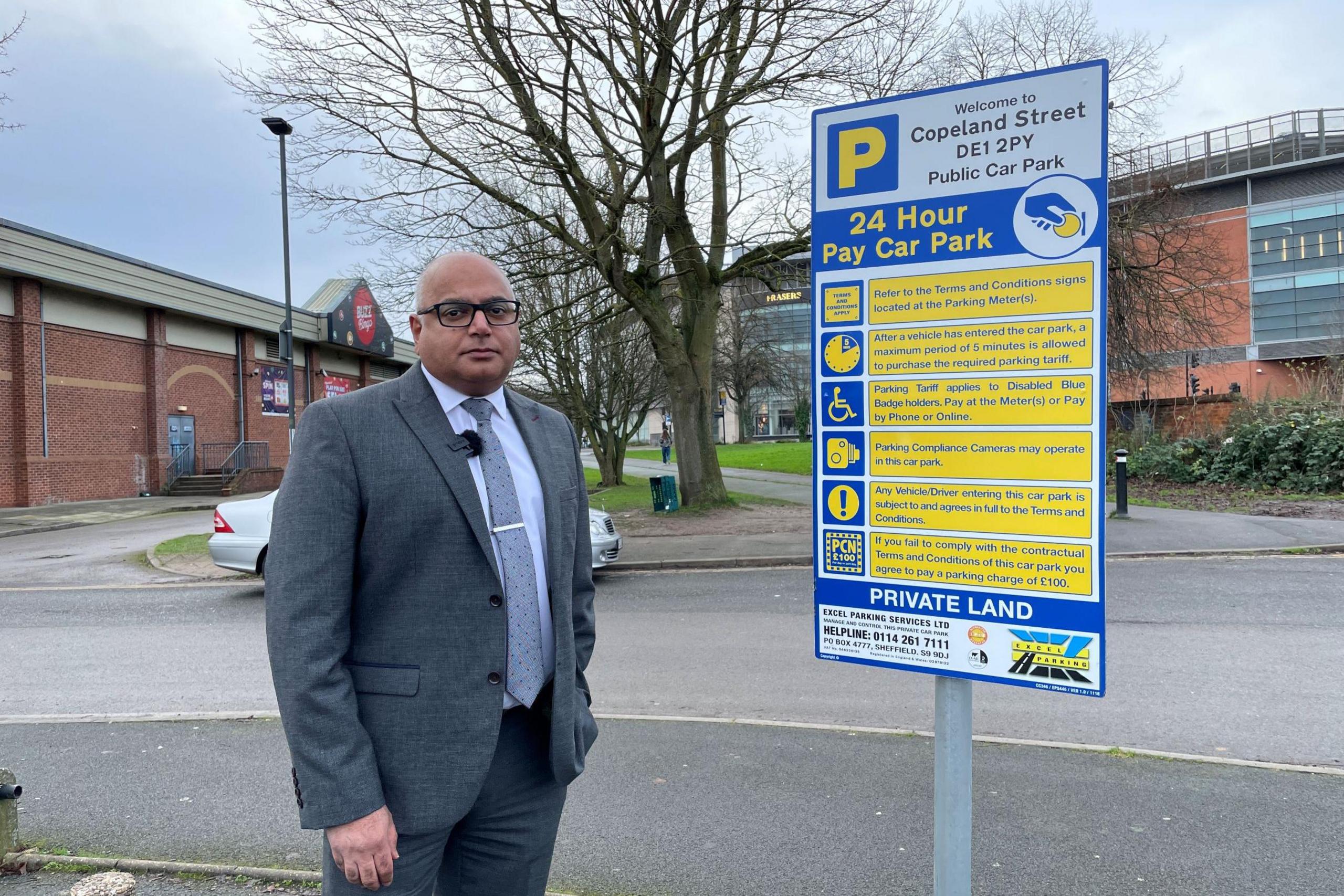 Baggy Shanker MP standing next to a sign at the Copeland Street car park in Derby