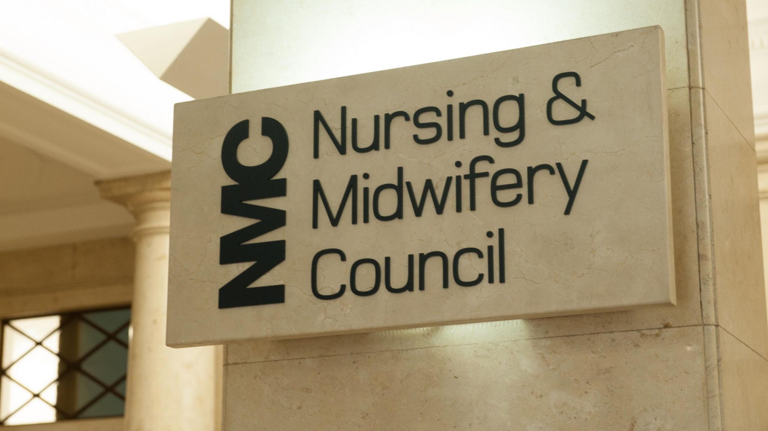 A sign outside a NMC building that appears to be made out of marble or stone and says "NMC: Nursing Midwifery Council" 