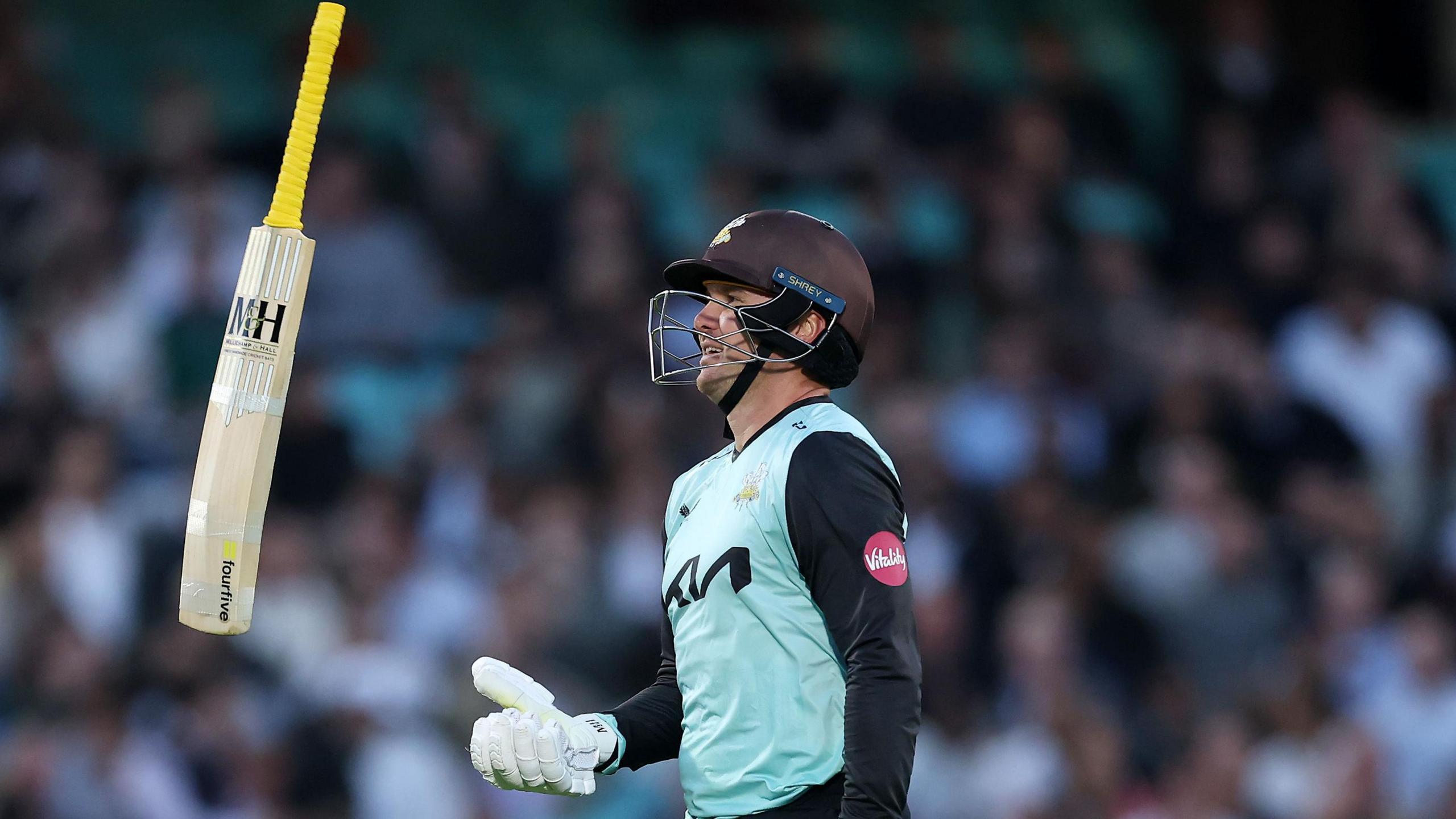 Jason Roy, batter for Surrey, wears a helmet and throws his bat up in the air in celebration
