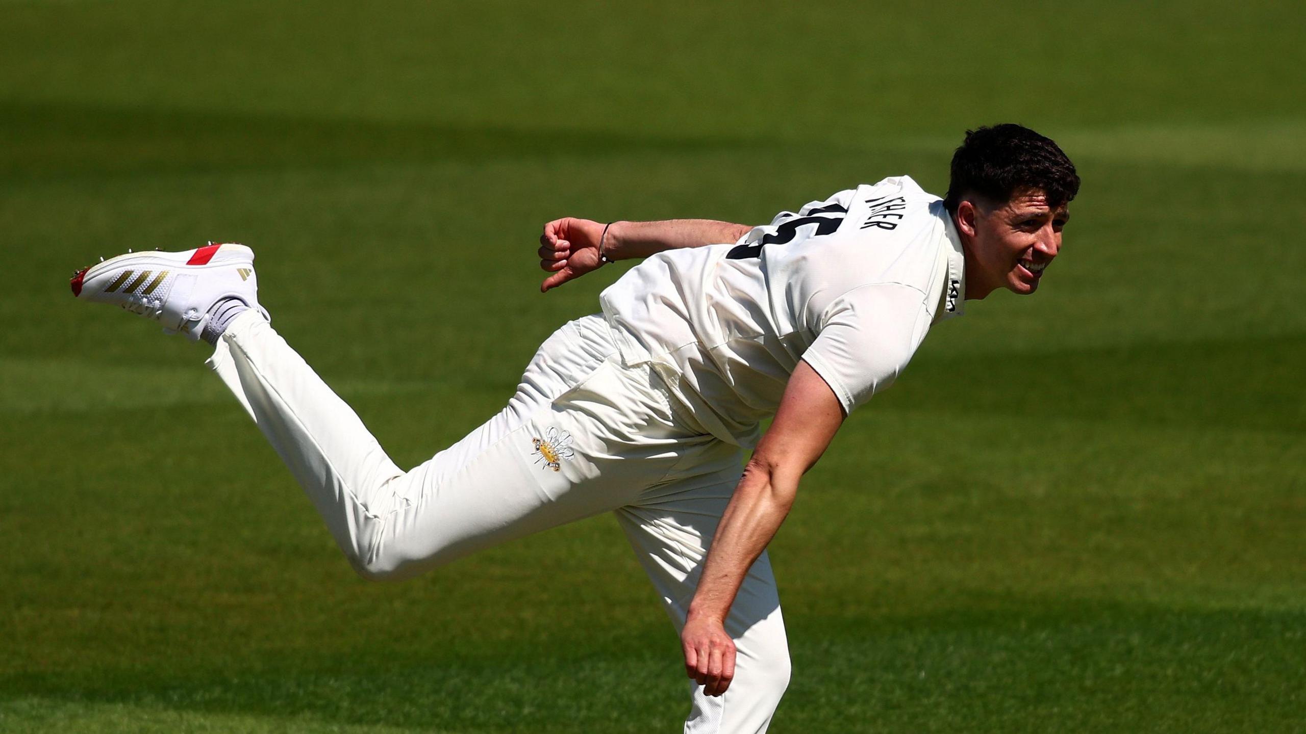 Matt Fisher bowling for Surrey in his follow-through