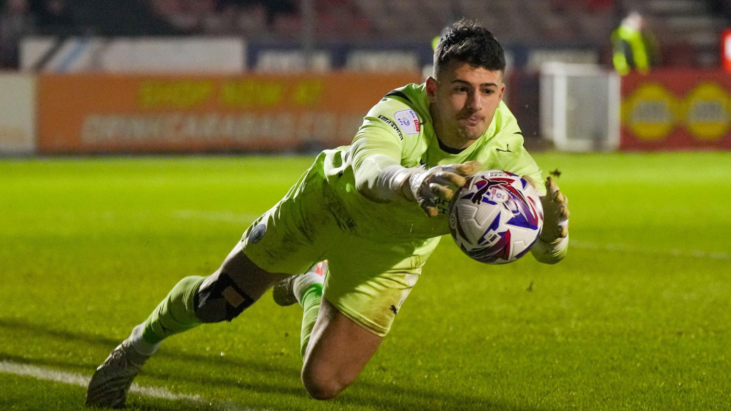 Wigan goalkeeper Sam Tickle reaches out to grab the ball
