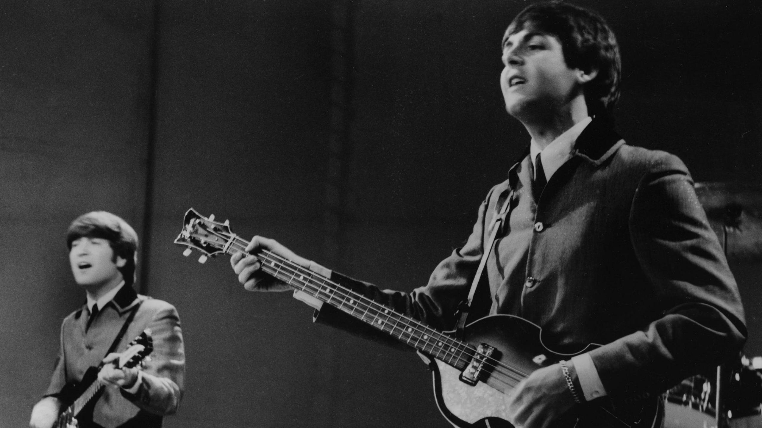 John Lennon left and Paul McCartney right singing in a black and white picture from 1964