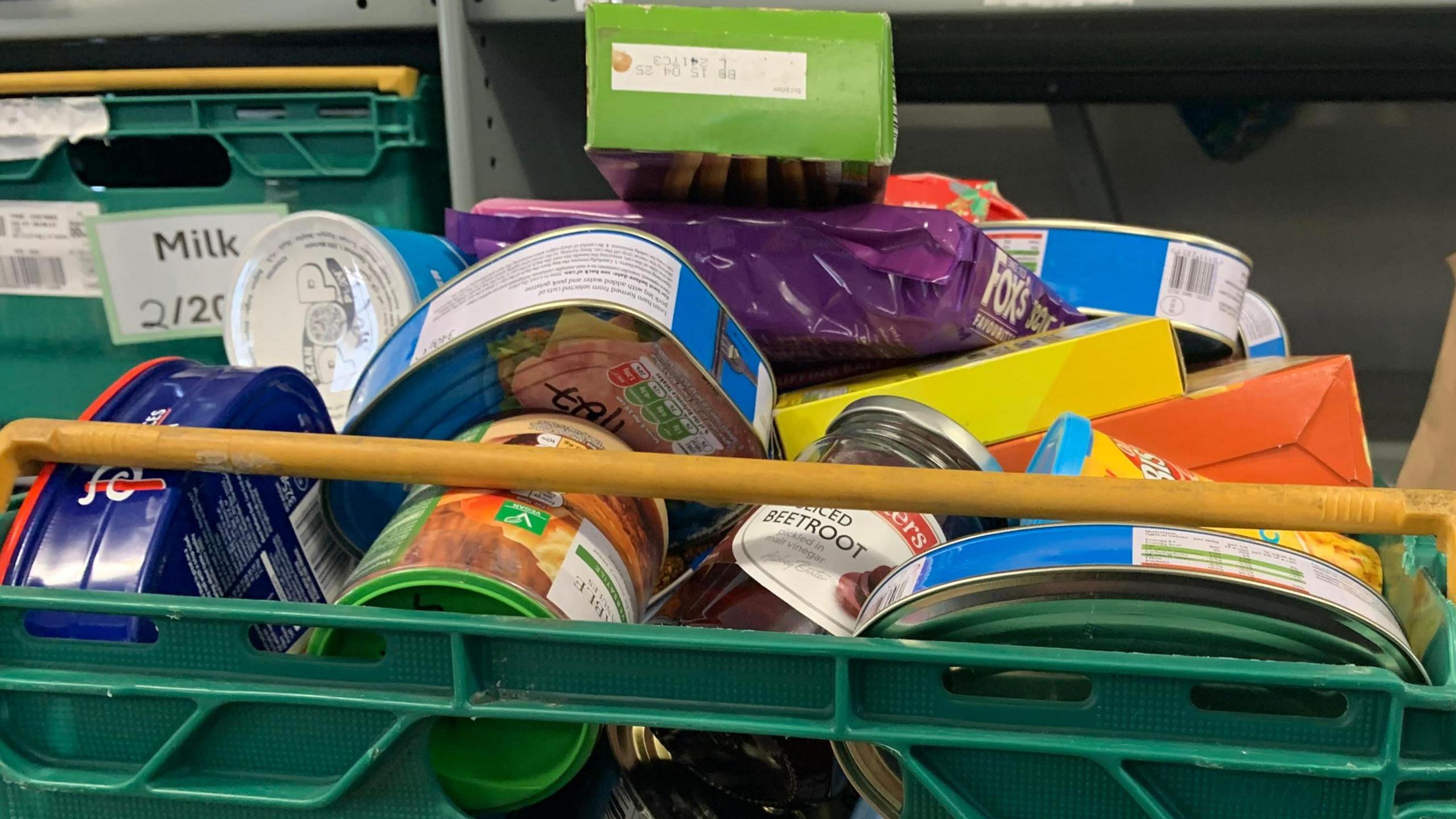 Green crate full of tins and biscuits. 