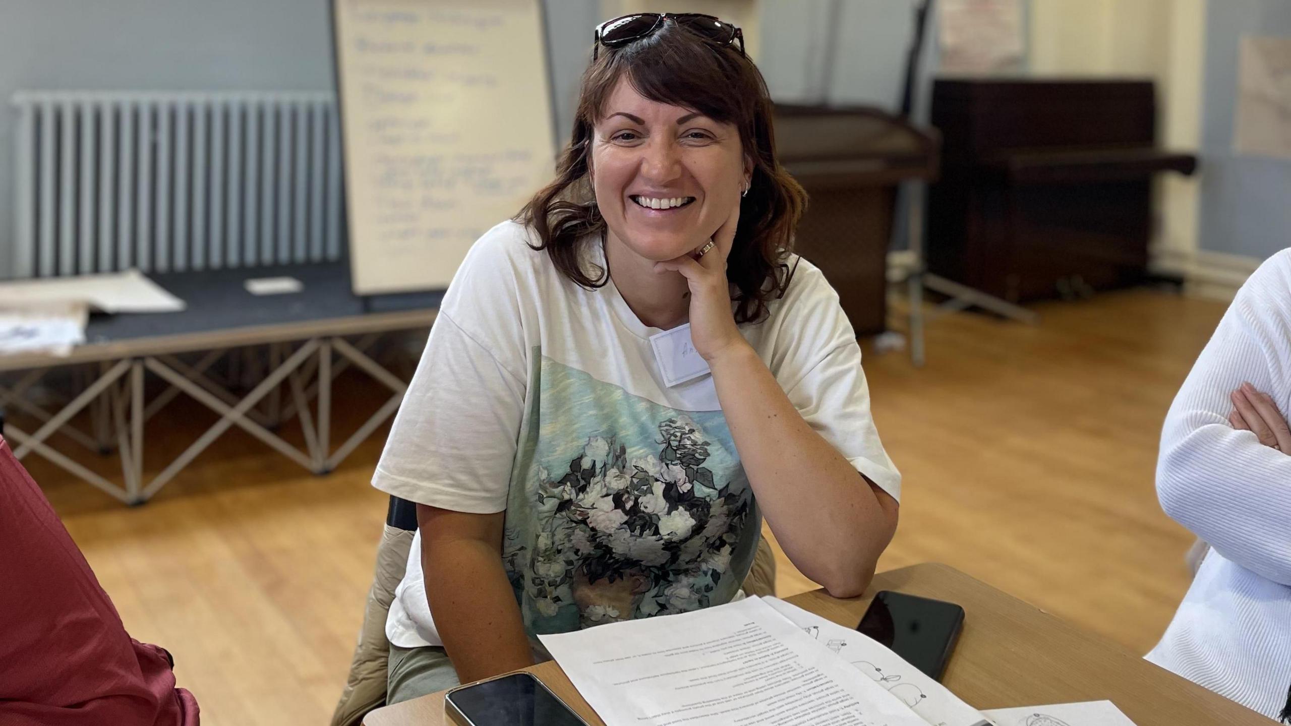 Anya, a volunteer, sitting down and smiling in front of a number of papers