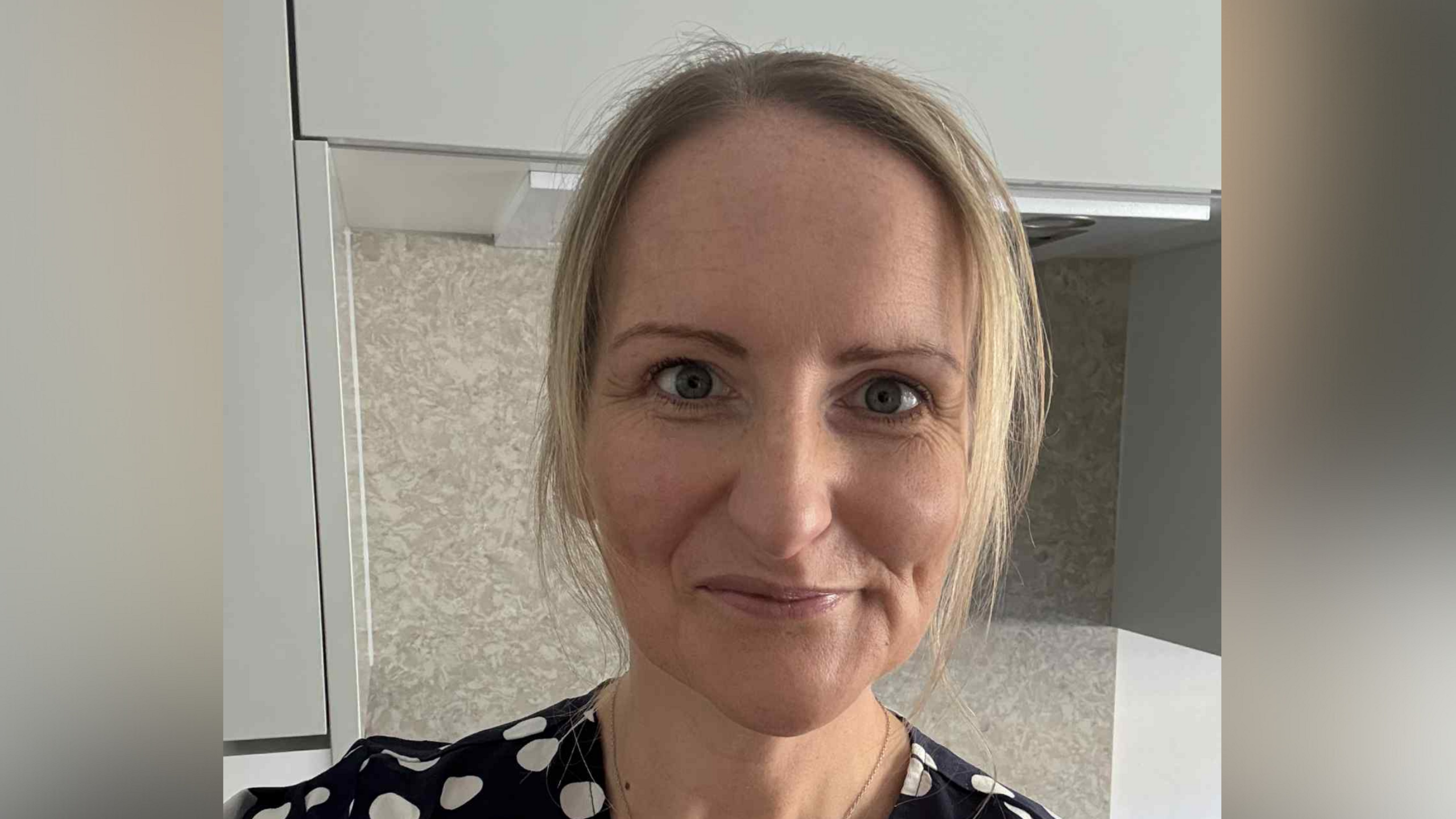 A selfie-style image of Clare Doughty. She has blonde hair and is wearing a black and white polka dot top. She is smiling into the camera.