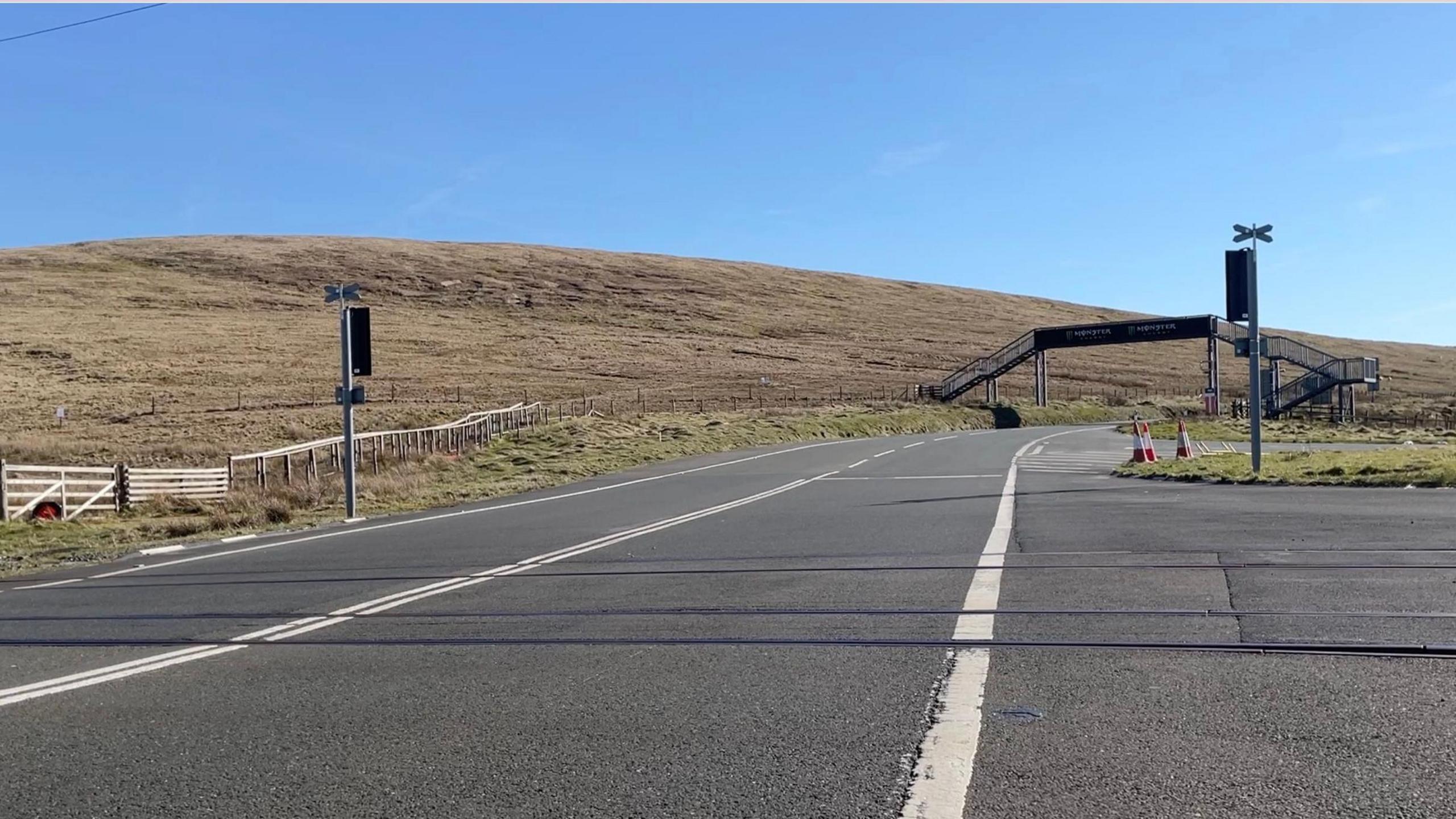 The Mountain Road, at the Bungalow, with a metal footbridge for people to cross the road.