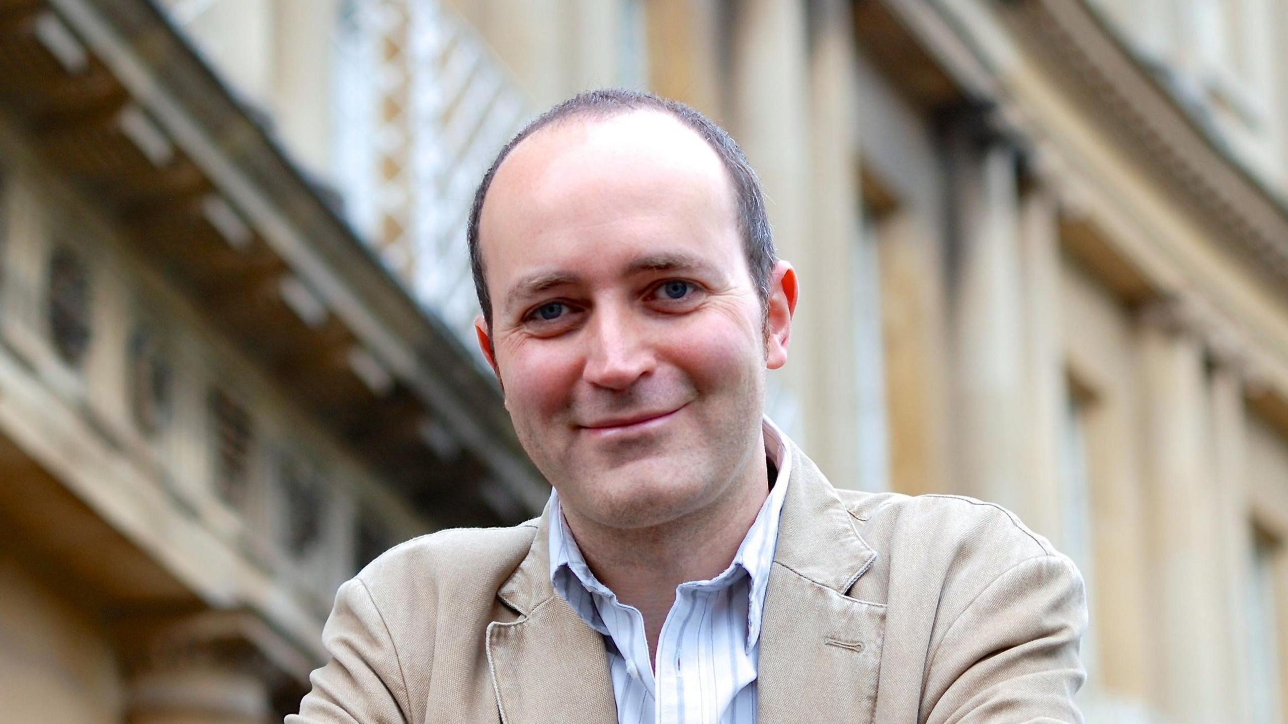 Dominic Tristram smiling in front of traditional Bath buildings