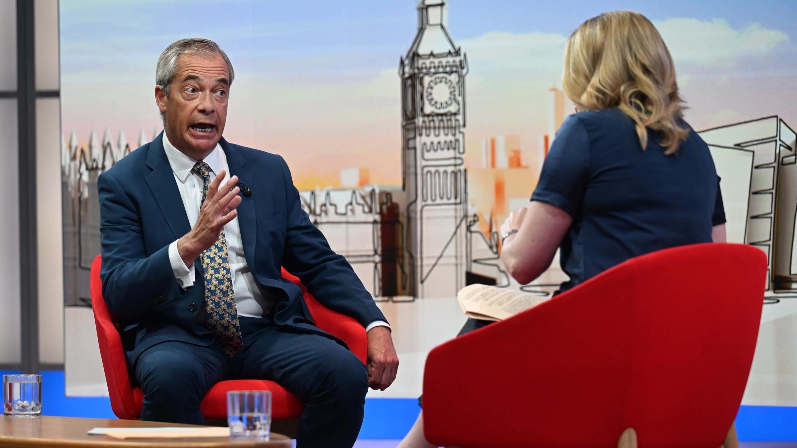 Nigel Farage being interviewed in a TV studio by the BBC's Laura Kuenssberg, who has her back to the camera.