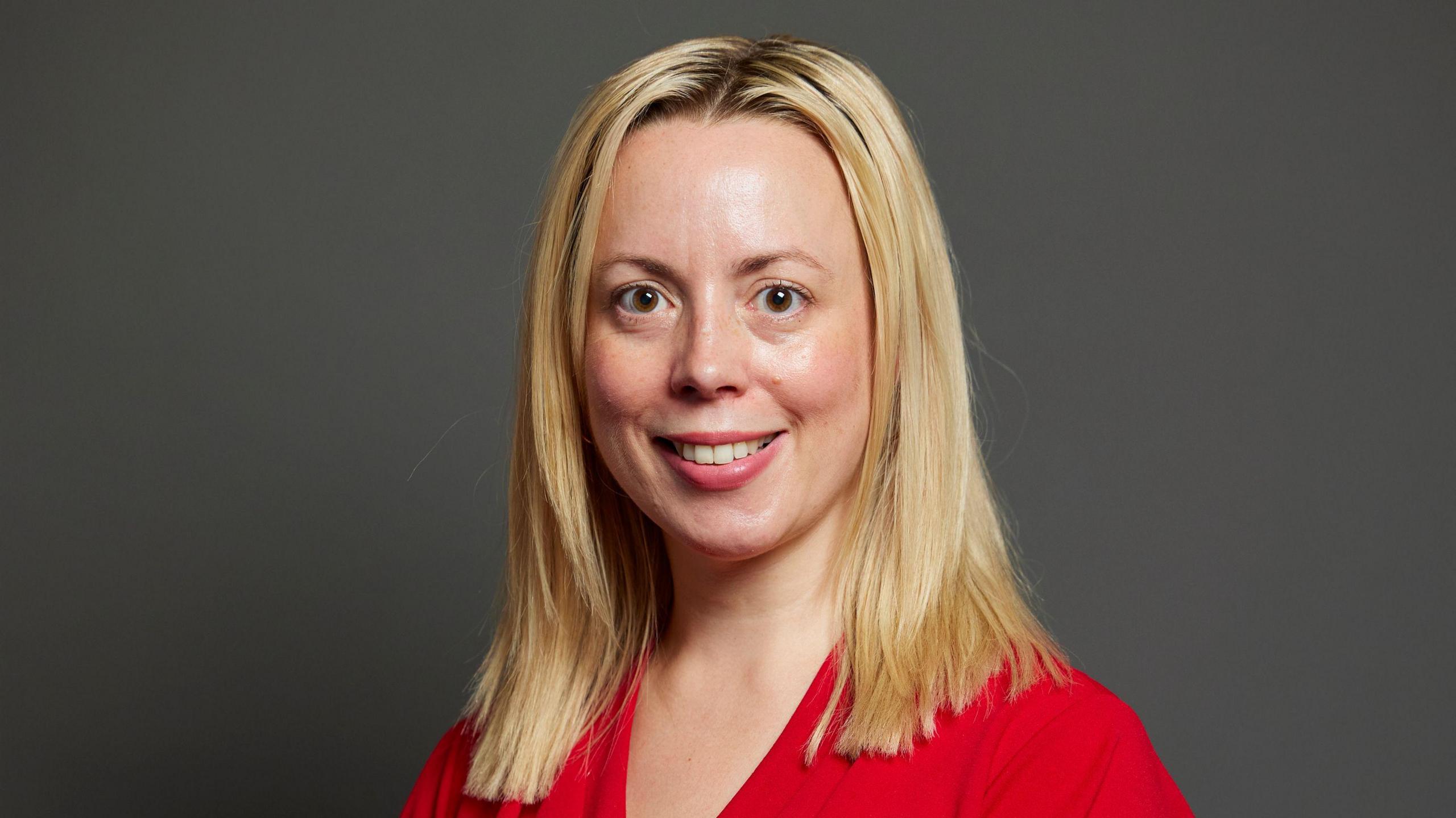 Parliamentary portrait of Sarah Hall, the Labour MP for Warrington South. She has mid-length blonde hair and a red blouse on.