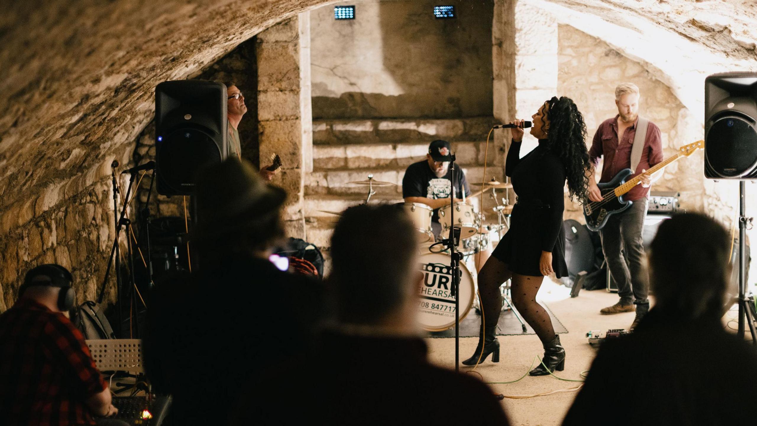 A female fronted band performs in a vault.