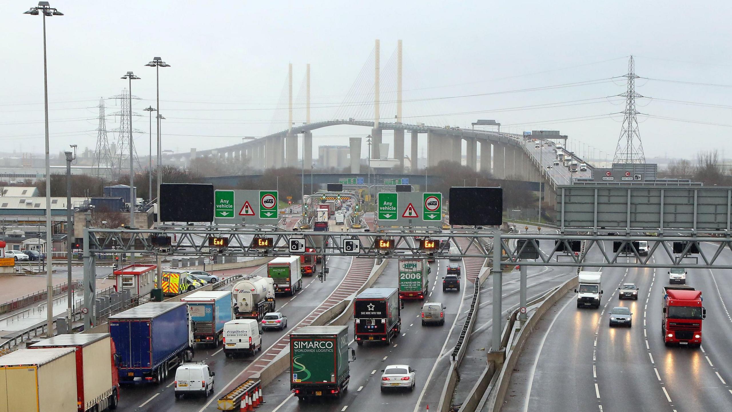 The Dartford Crossing.  Many lorries queuing to enter the Dartford tunnels on the Kent side with the QE2 bridge in the centre of the picture only a grey slightly misty day.