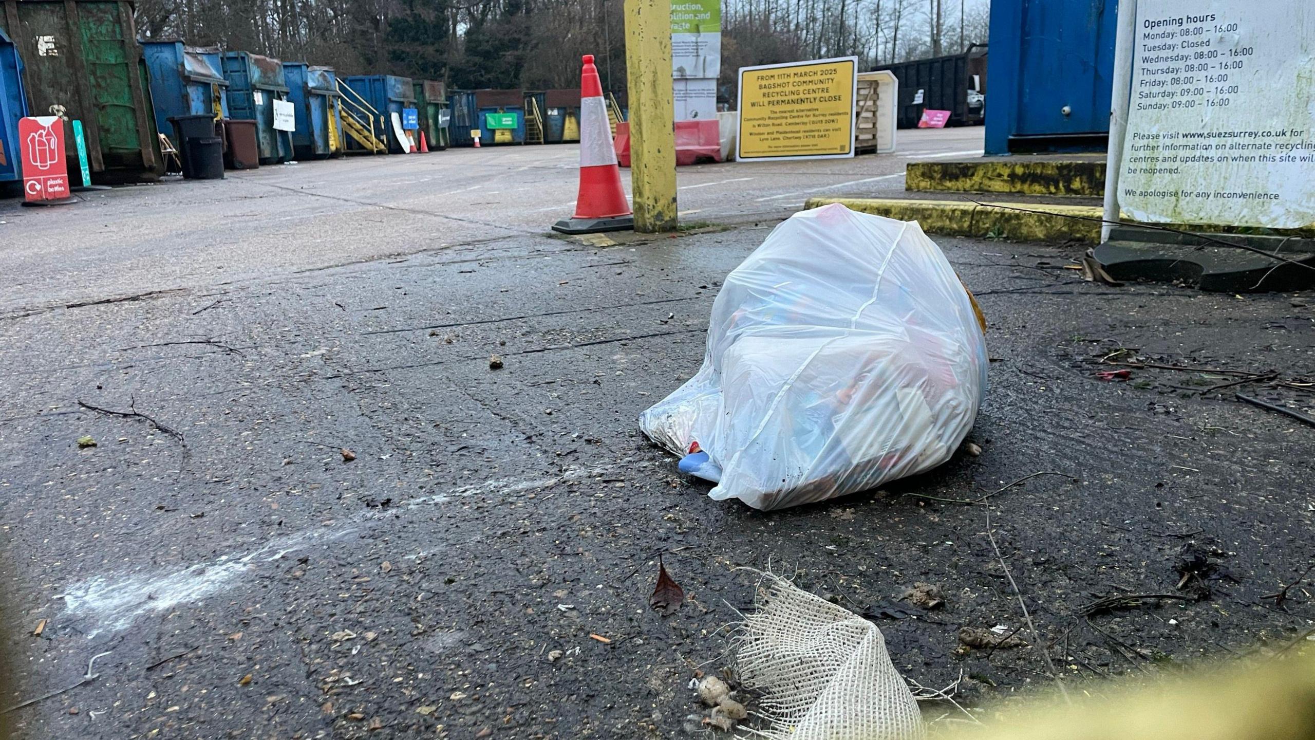  A recycling centre with a white bag of rubbish on the floor.