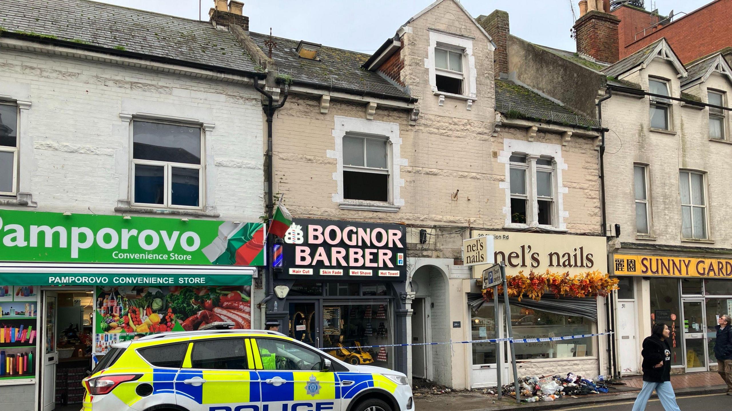 A police car parked outside the scene of a fire in a flat above several shops in Station Road, Bognor Regis.