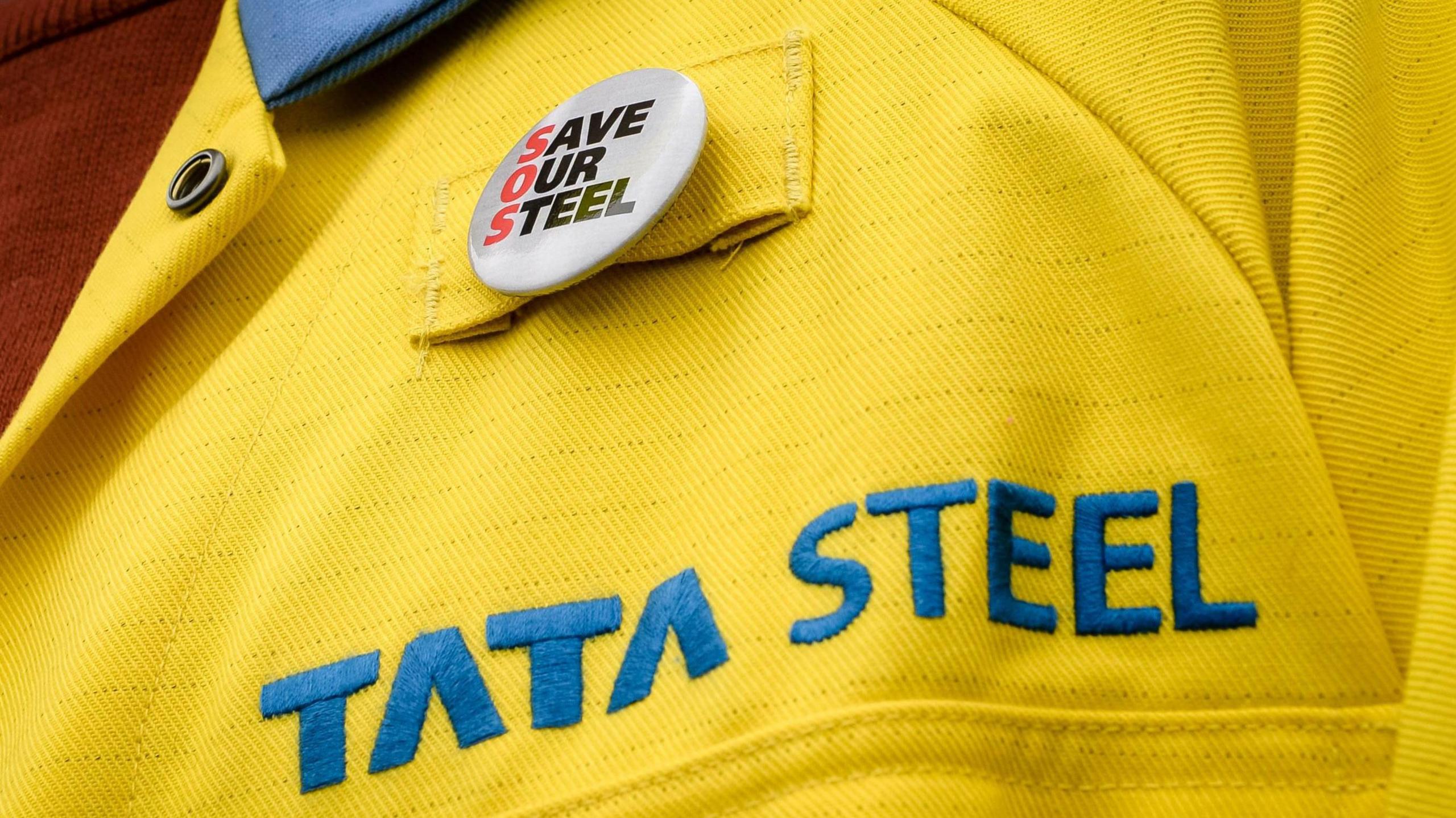 A close-up of a yellow Tata Steel jacket with a 'Save our Steel' badge pinned to it.