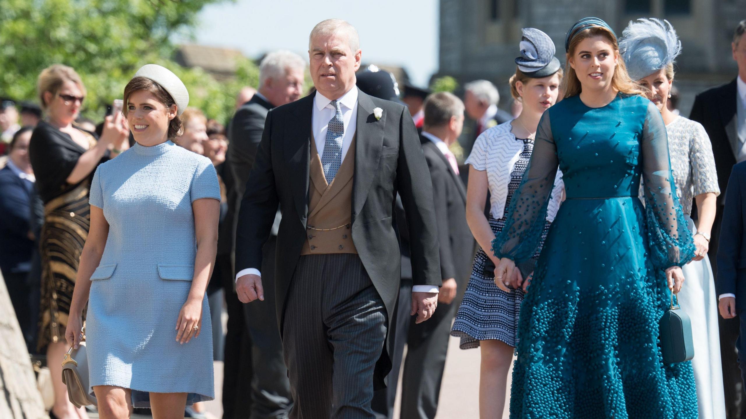 The princesses wearing blue and turquoise dresses pictured with their father at the wedding of Harry and Meghan in 2018