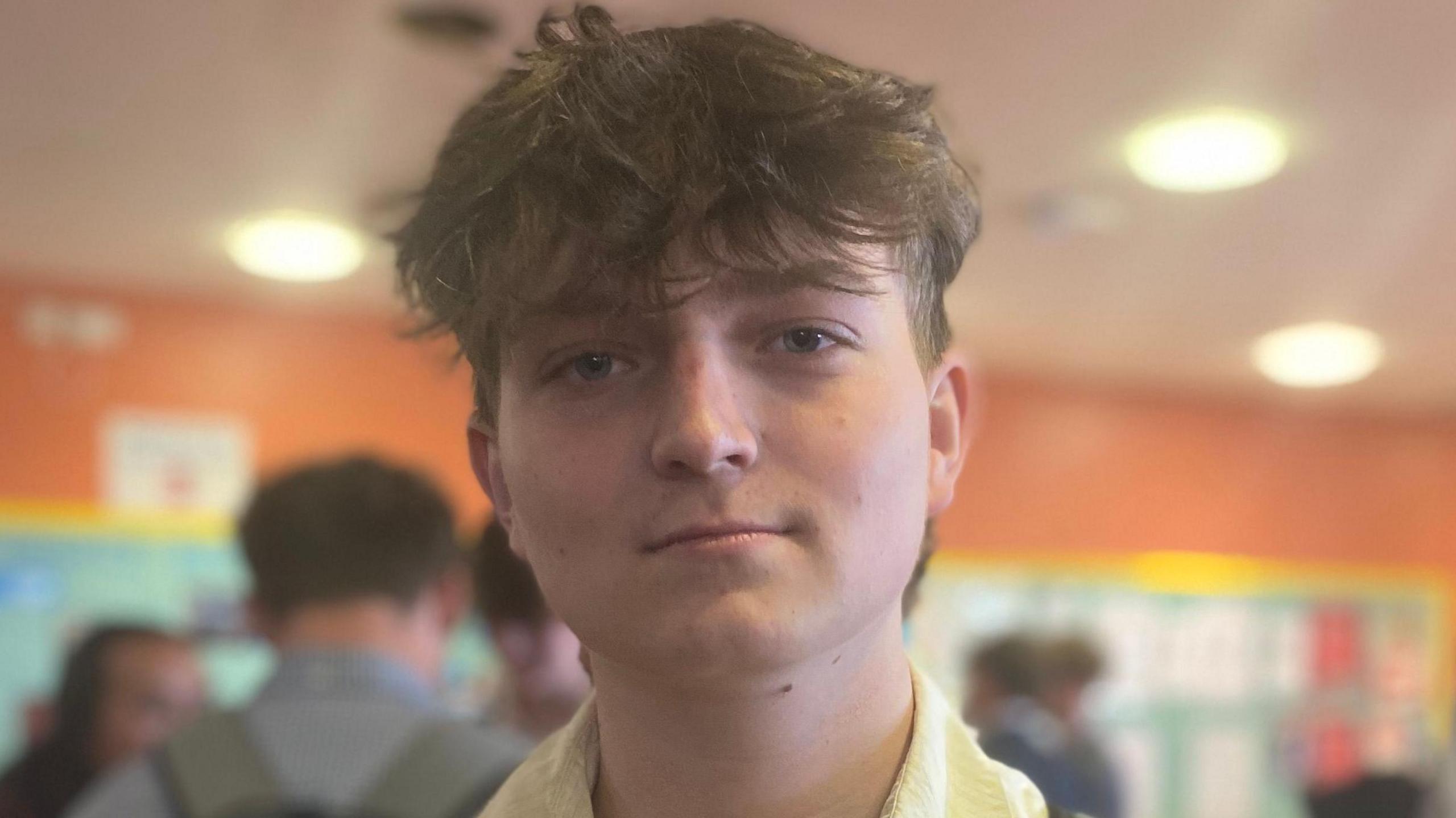A boy with messy brown hair looking towards the camera.