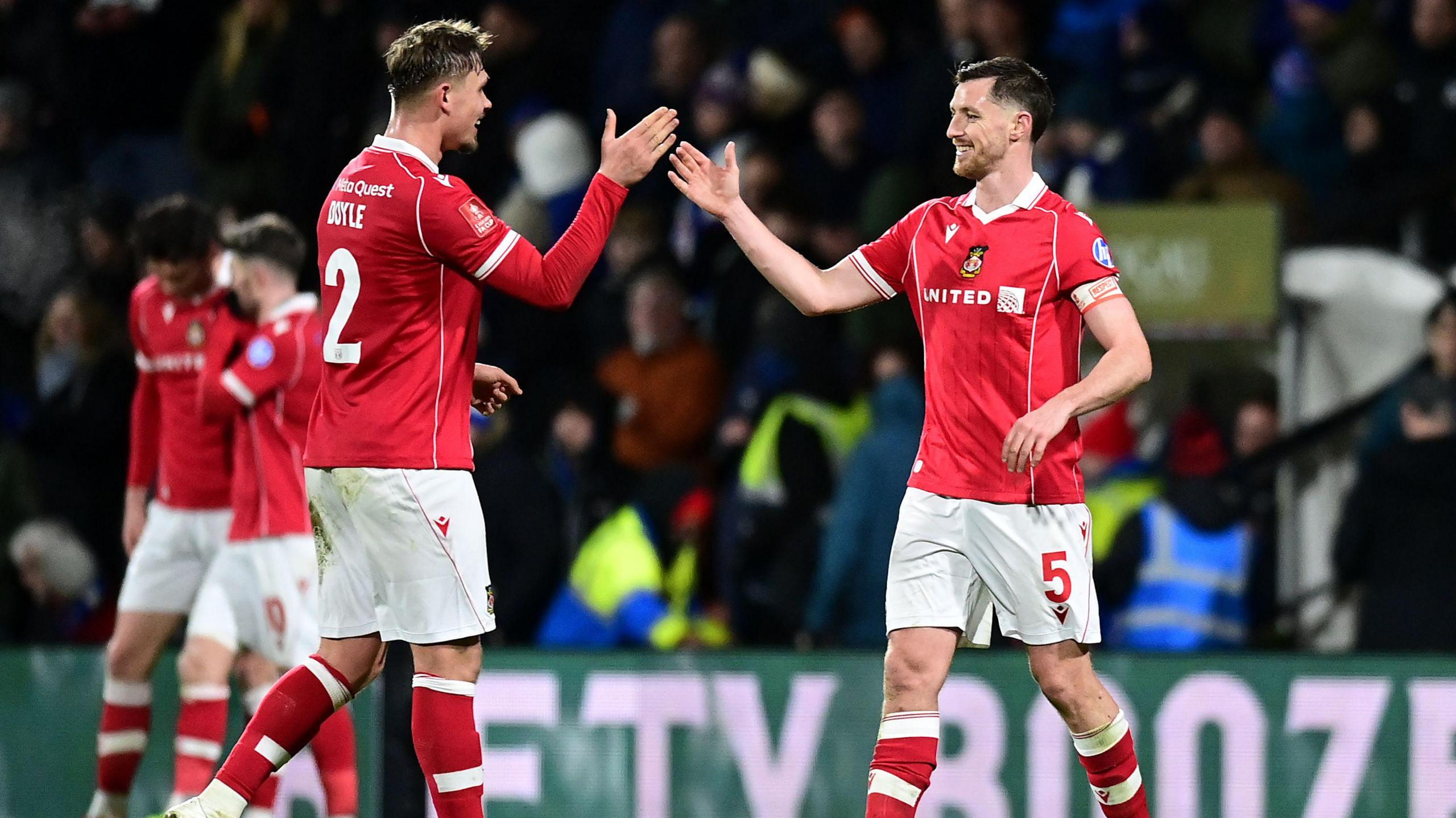 Wrexham's Dominic Hyam celebrates with team-mate Callum Doyle at the final whistle during the Emirates FA Cup Fourth Round match between Wrexham and Ipswich Town