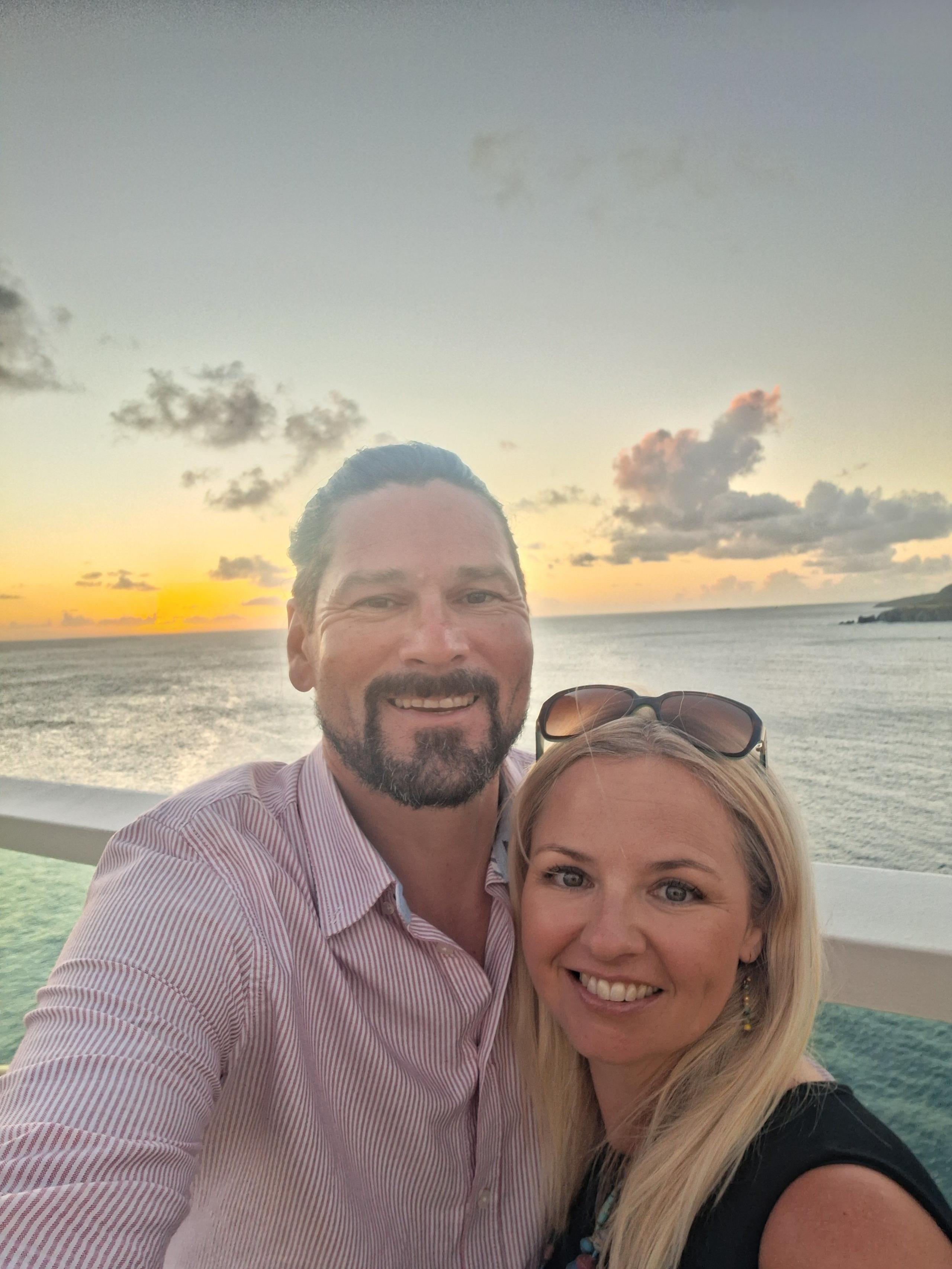 Man and woman smiling in front of the sea and sunset 