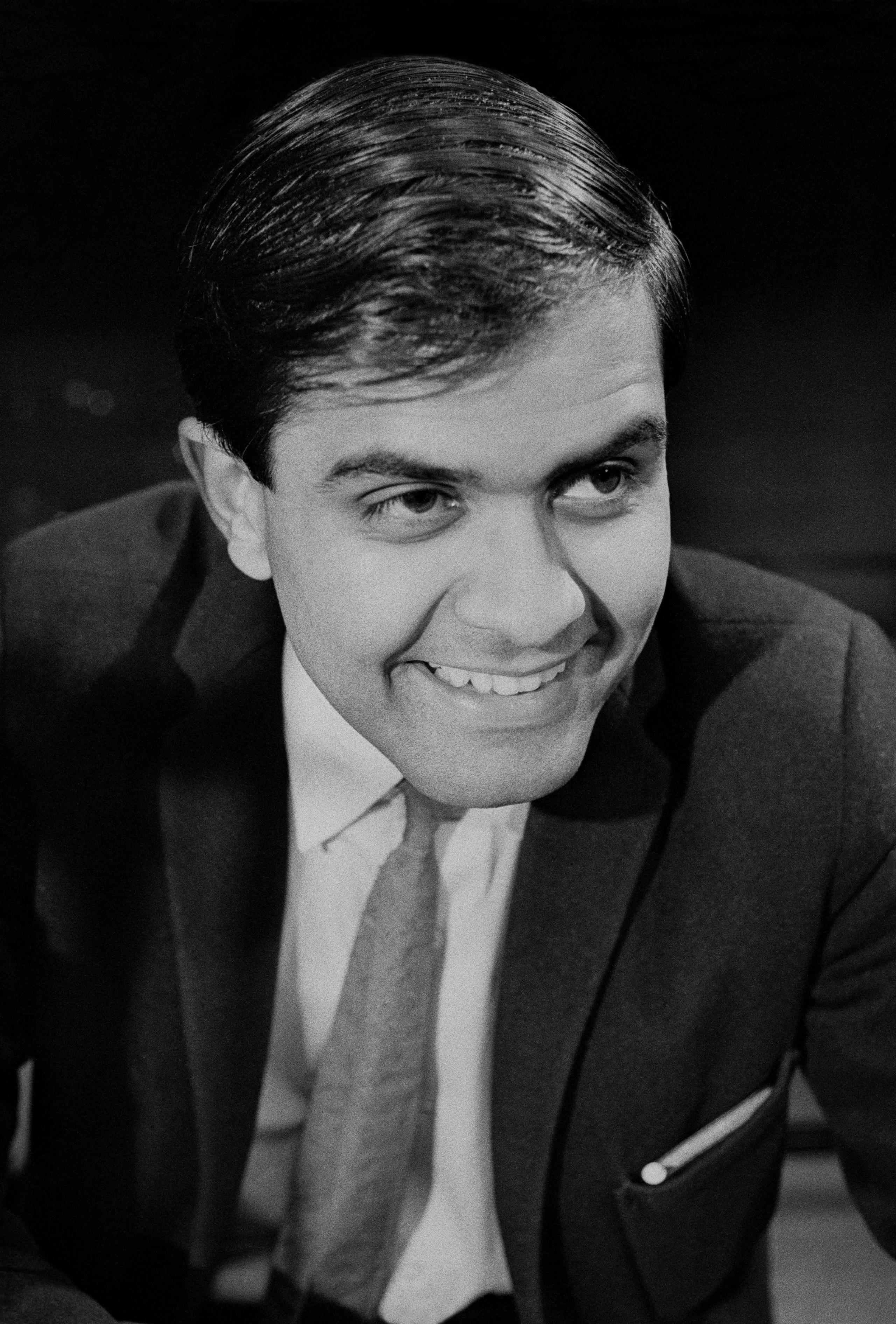 Black and white portrait of a young Waris Hussein smiling and looking into the distance