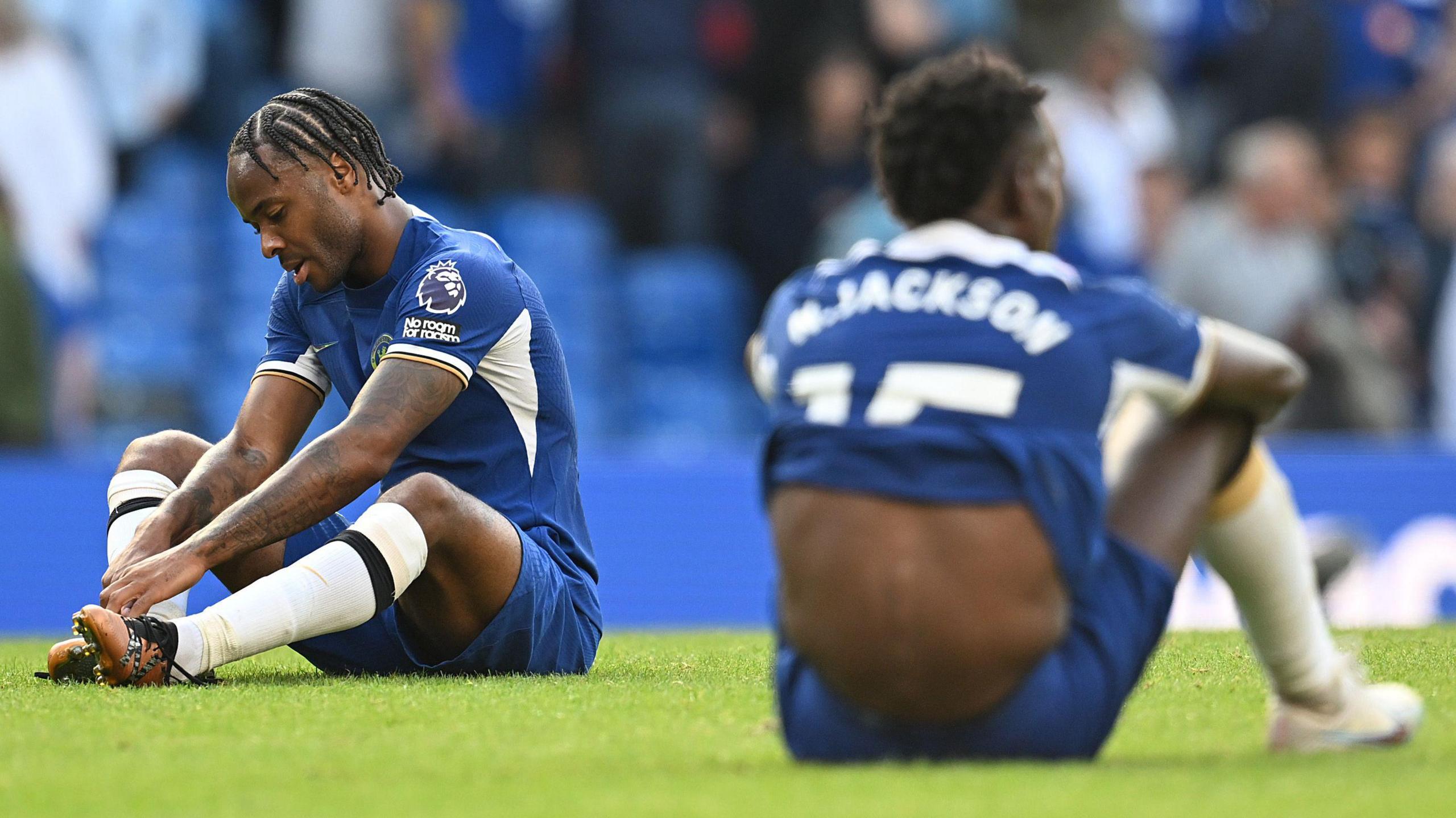 Raheem Sterling and Nicolas Jackson sit dejected on the turf