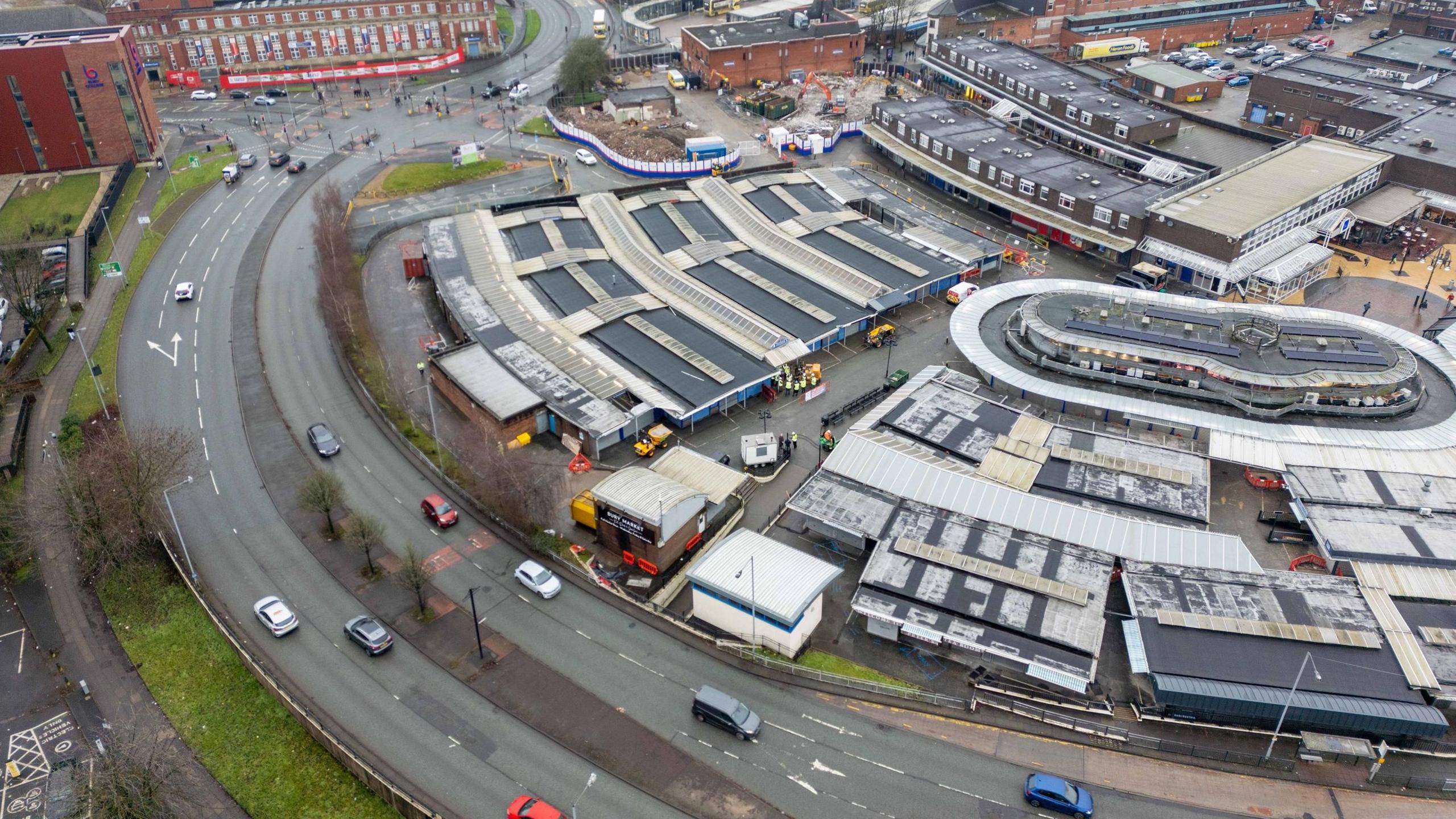 Drone view of the top of Bury Market, showing covered areas next to a road curving around it.