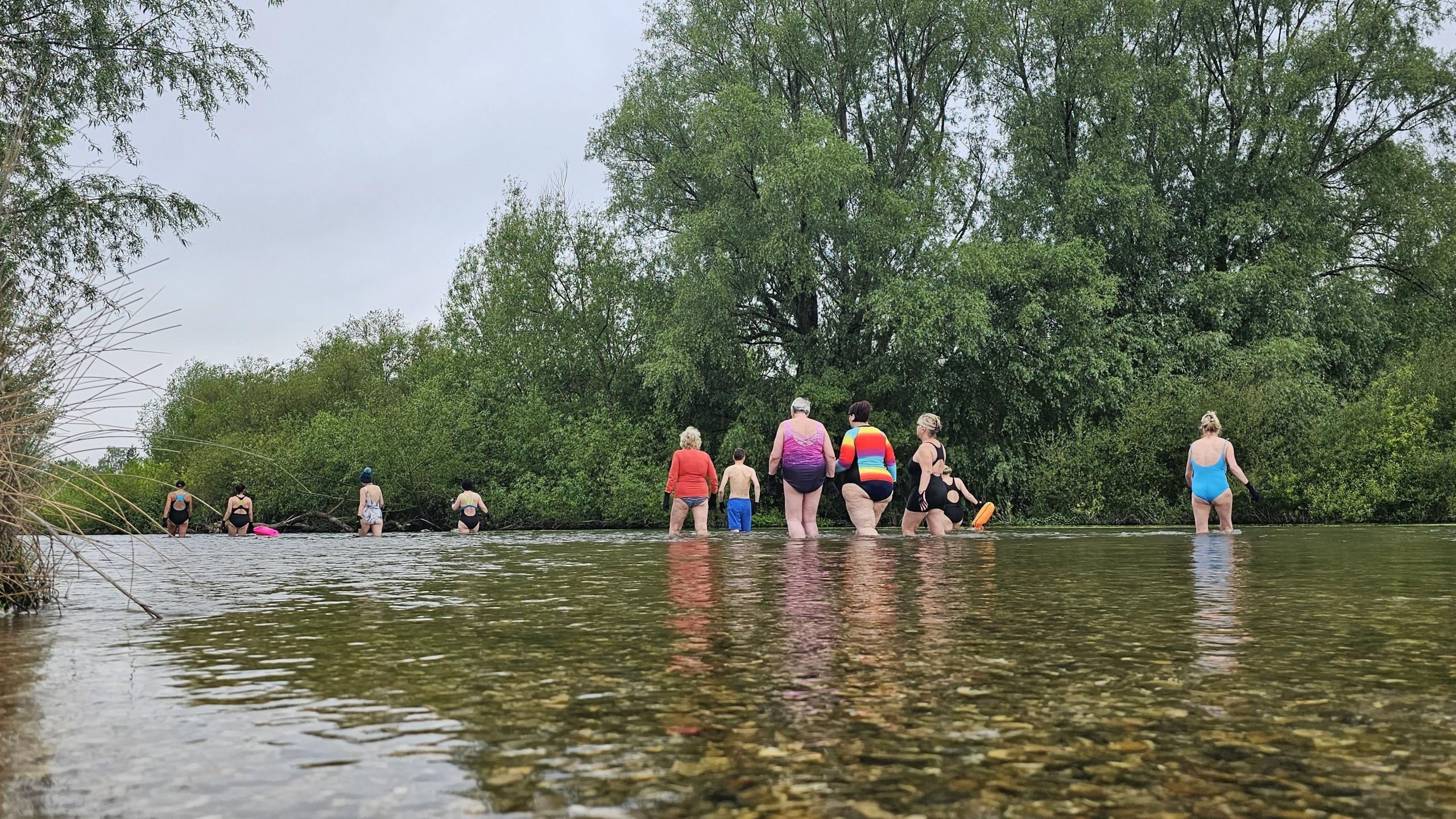 A group of wild swimmers walking out into the river at Fordingbridge