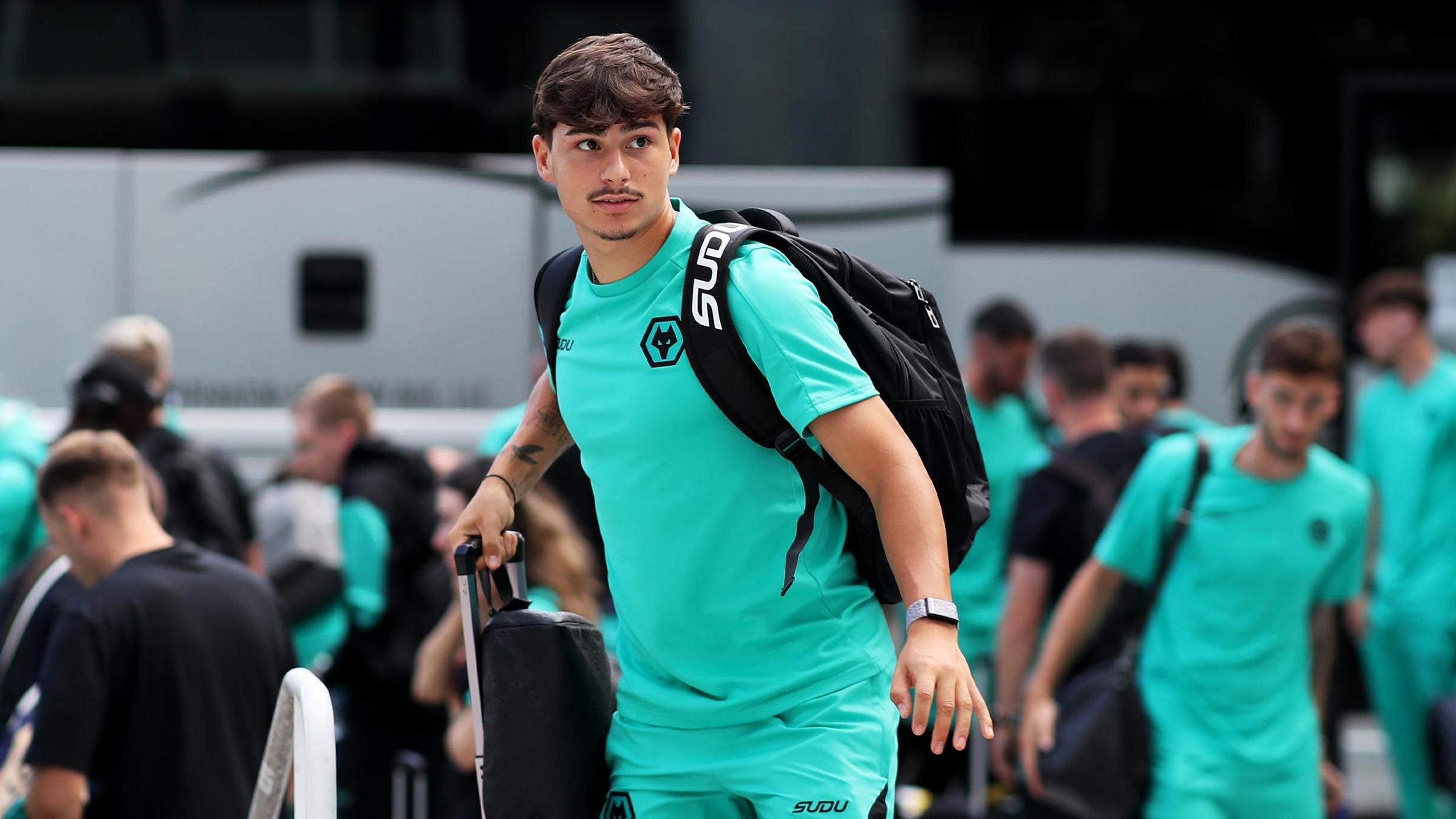 Wolves players dressed in green club T-shirts pictured on their arrival in the US. In the foreground is Rodrigo Gomes, with a pull-along suitcase and black rucksack