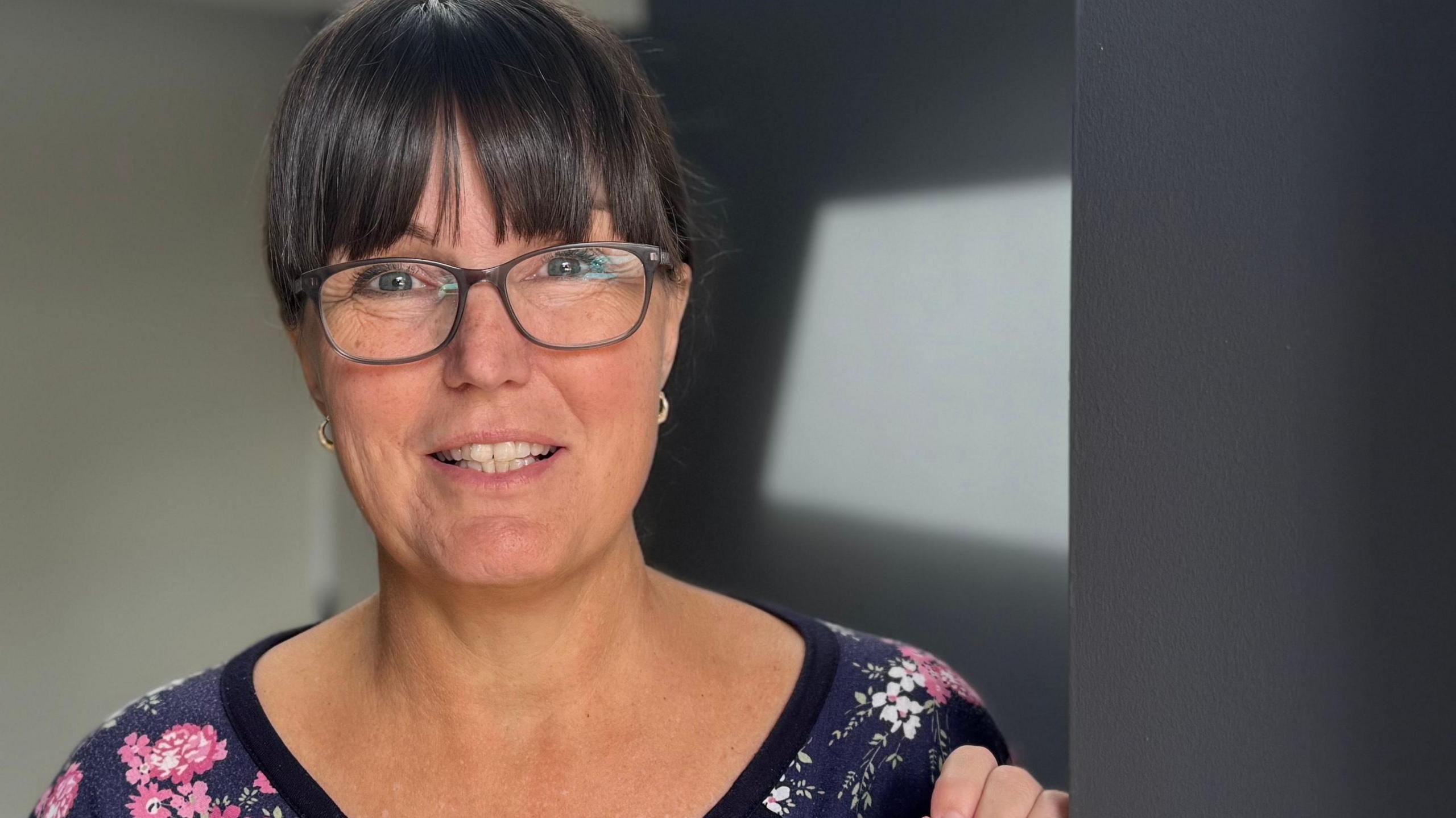 A head and shoulders image of Charlene Payne. She is wearing glasses and standing in her doorway. She is looking directly into the camera.