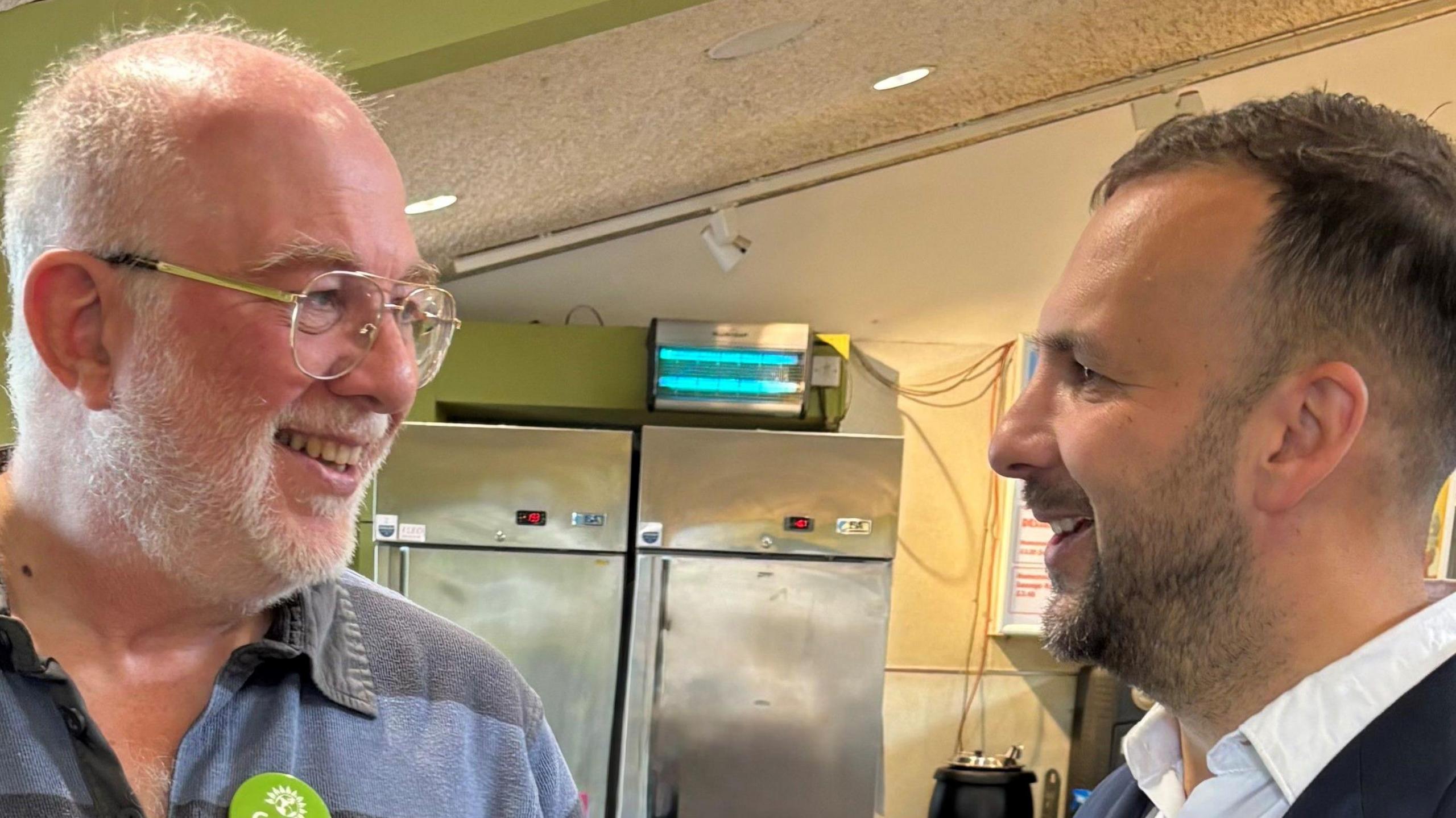 John Knight (on the left of the image) with Green Party leader Zack Polanski. The men, who are smiling at each other, appear to be standing in an industrial kitchen.