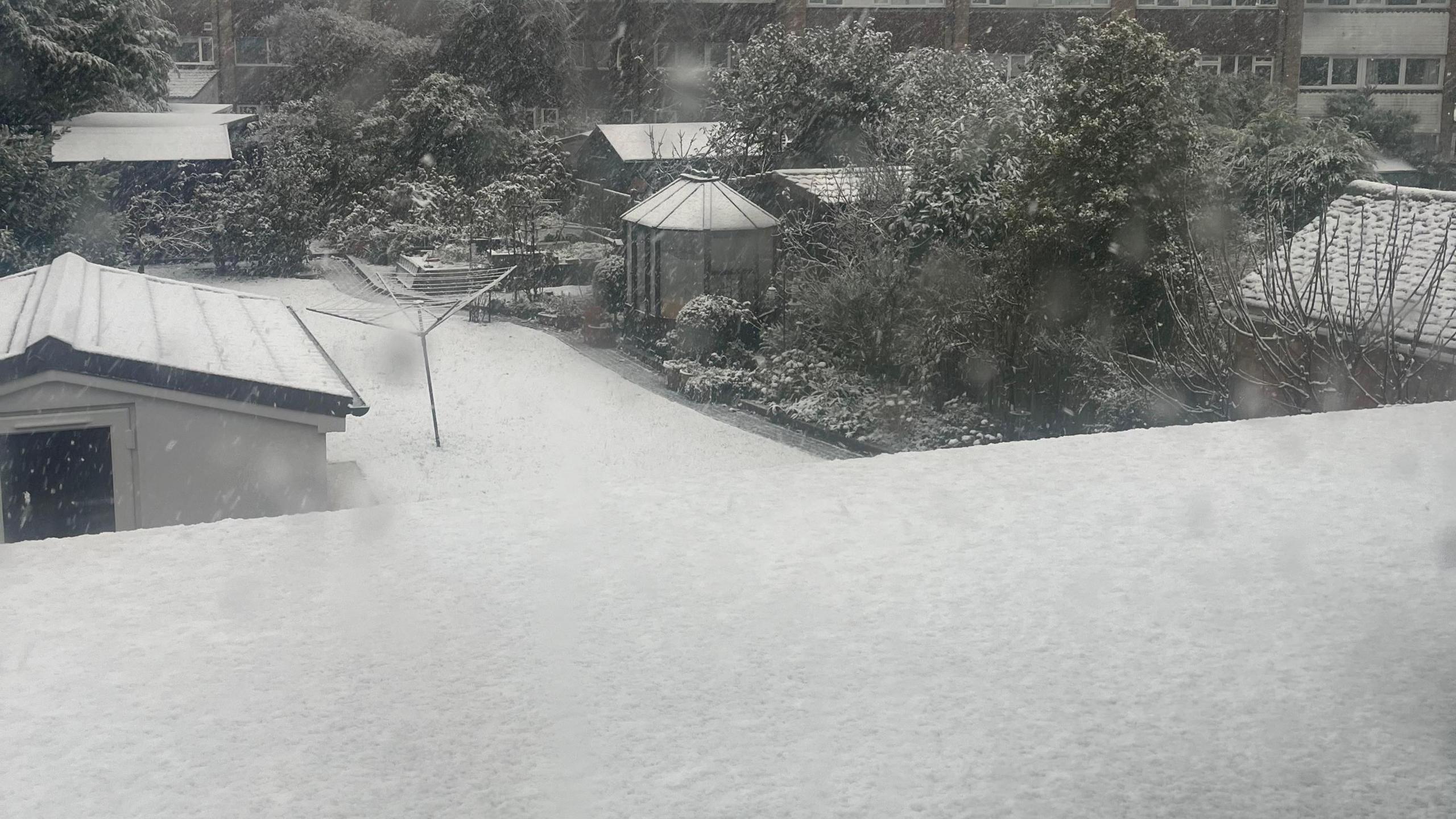 A soft blanket of snow covered roofs and lawns in Hughenden, Buckinghamshire. The photo is in black and white.