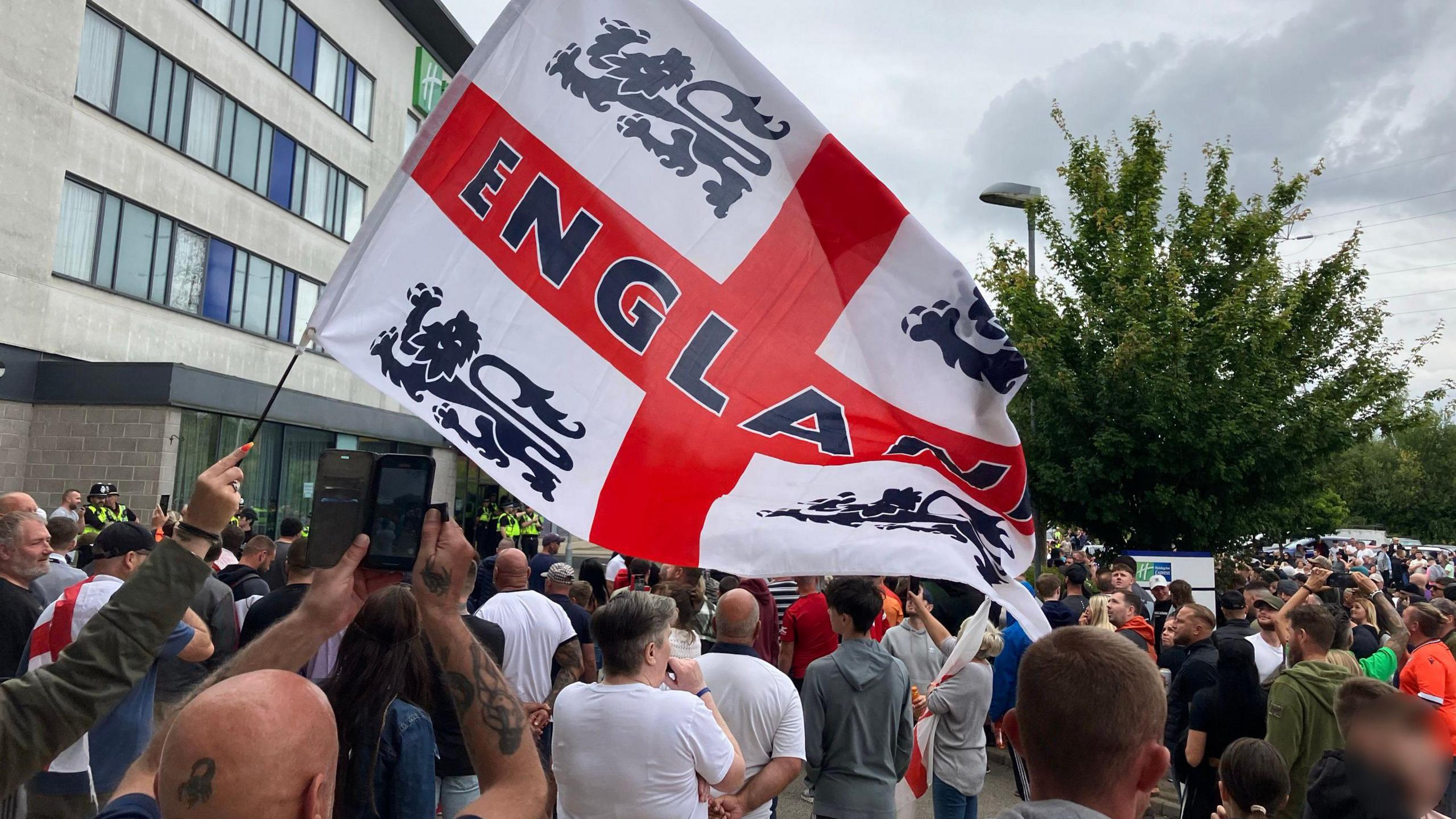 A group of protesters holding a giant England flag