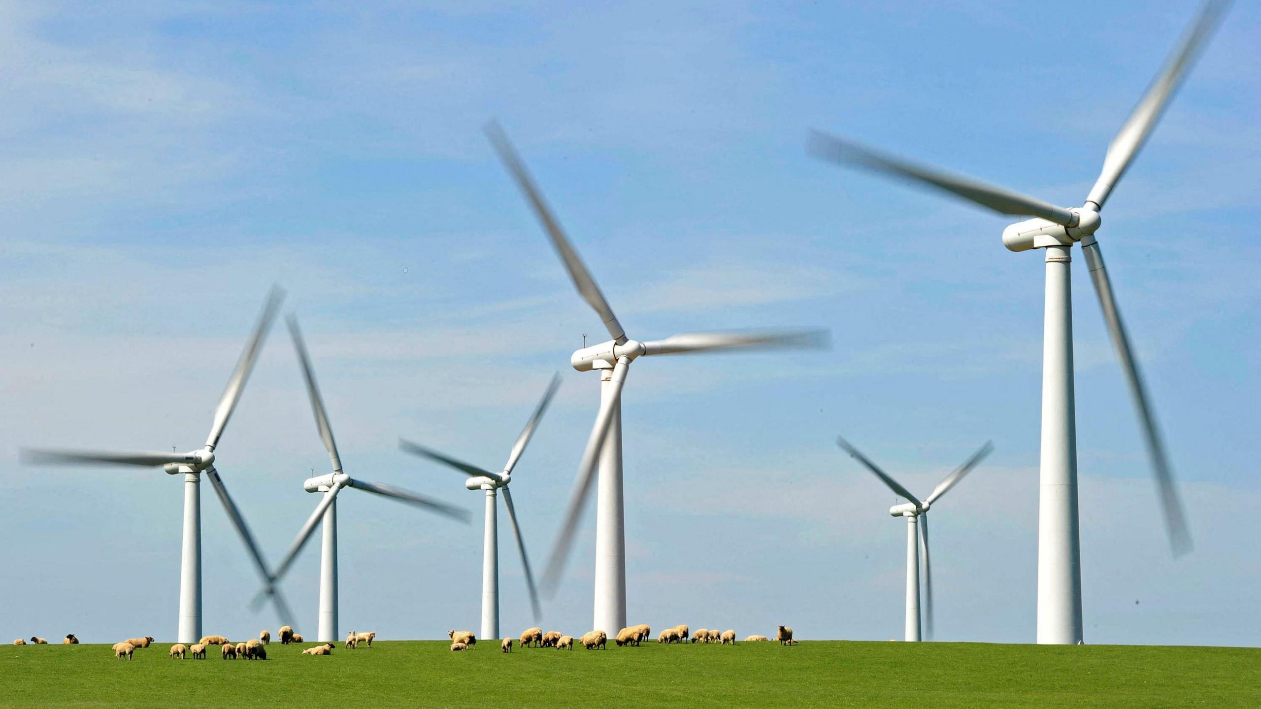 A windfarm is seen on Anglesey, north Wales with hills in the foreground