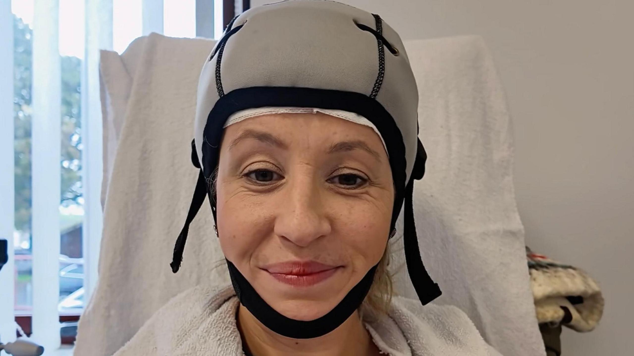 Presenter Mari Grug smiling wearing a cold cap in hospital, receiving cancer treatment